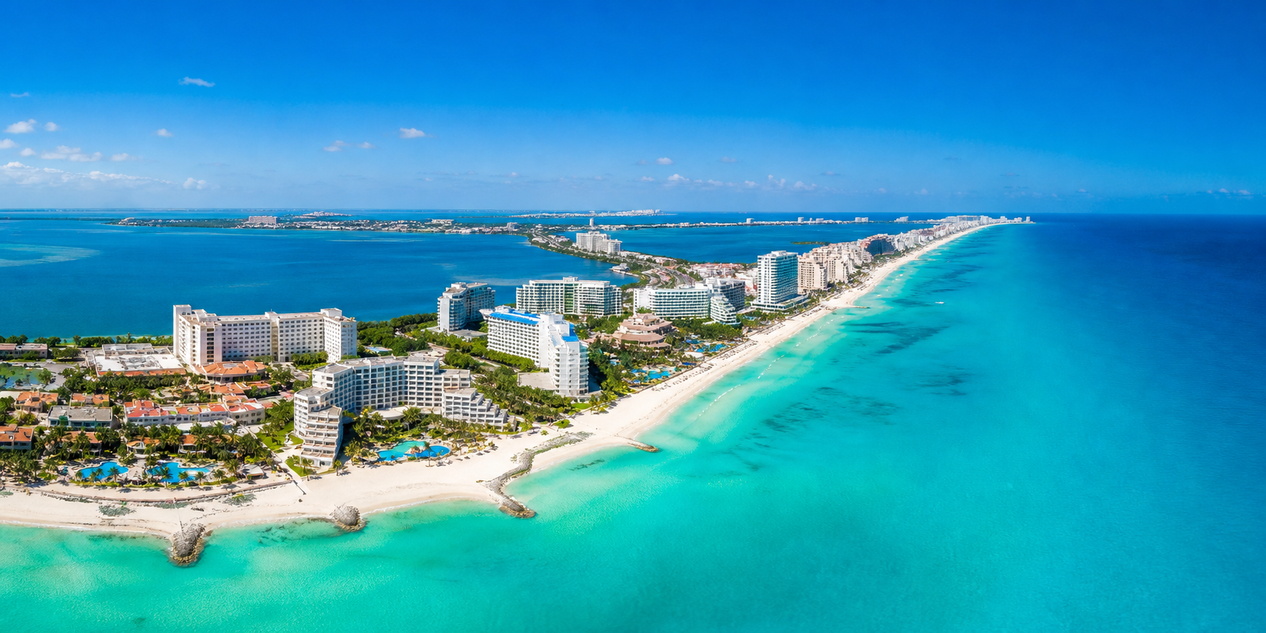 Vista panorámica de Cancún con playas de arena blanca y aguas turquesa del mar Caribe, destacando la icónica Zona Hotelera con modernos hoteles.