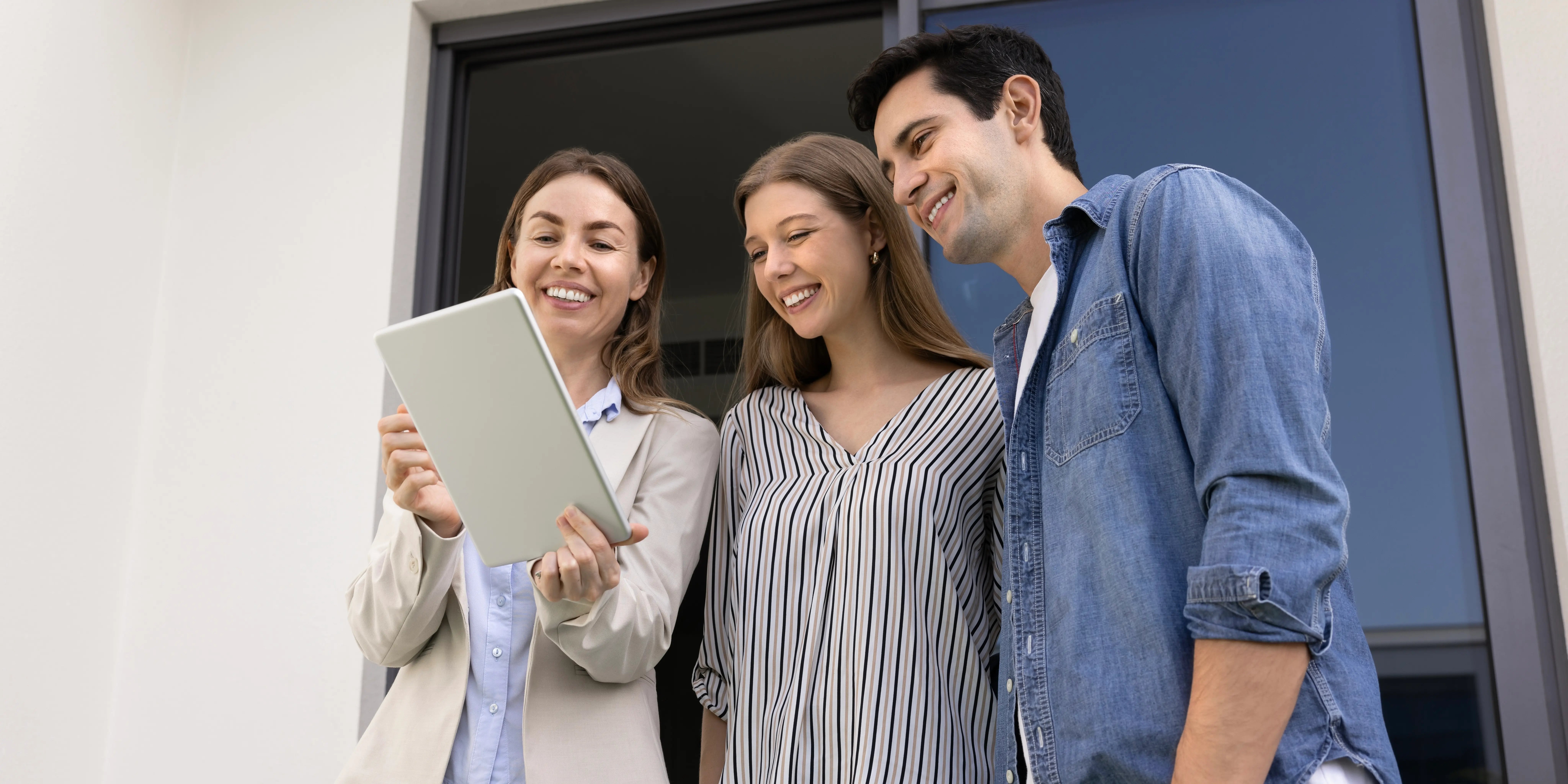 Agente inmobiliario que muestra una casa a una pareja joven y les explica los pasos para sacar un crédito hipotecario