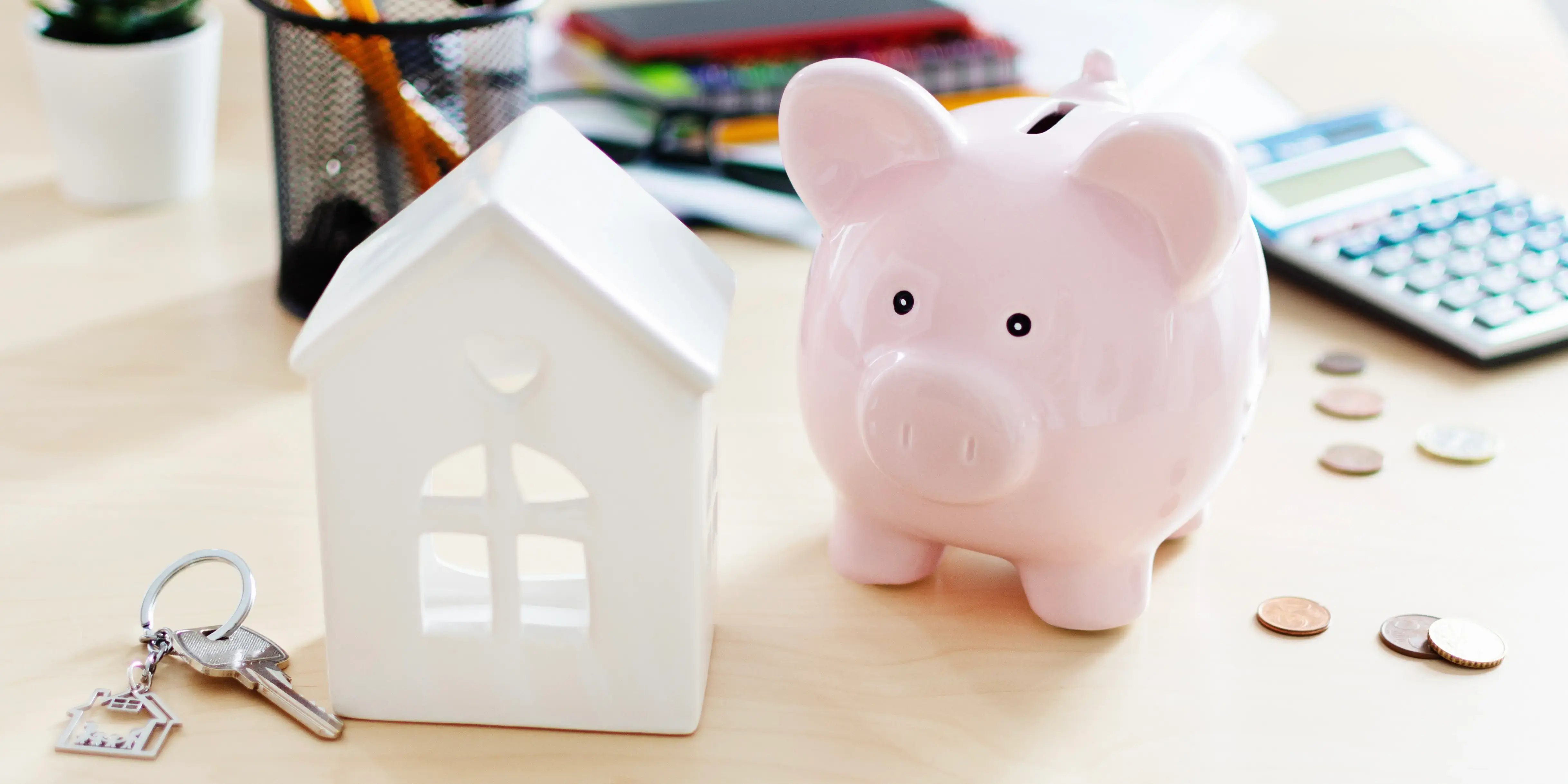 Alcancía de cerdo, modelo de casa sobre una mesa y calculadora, sacando cuentas de cuánto hay en la subcuenta de vivienda