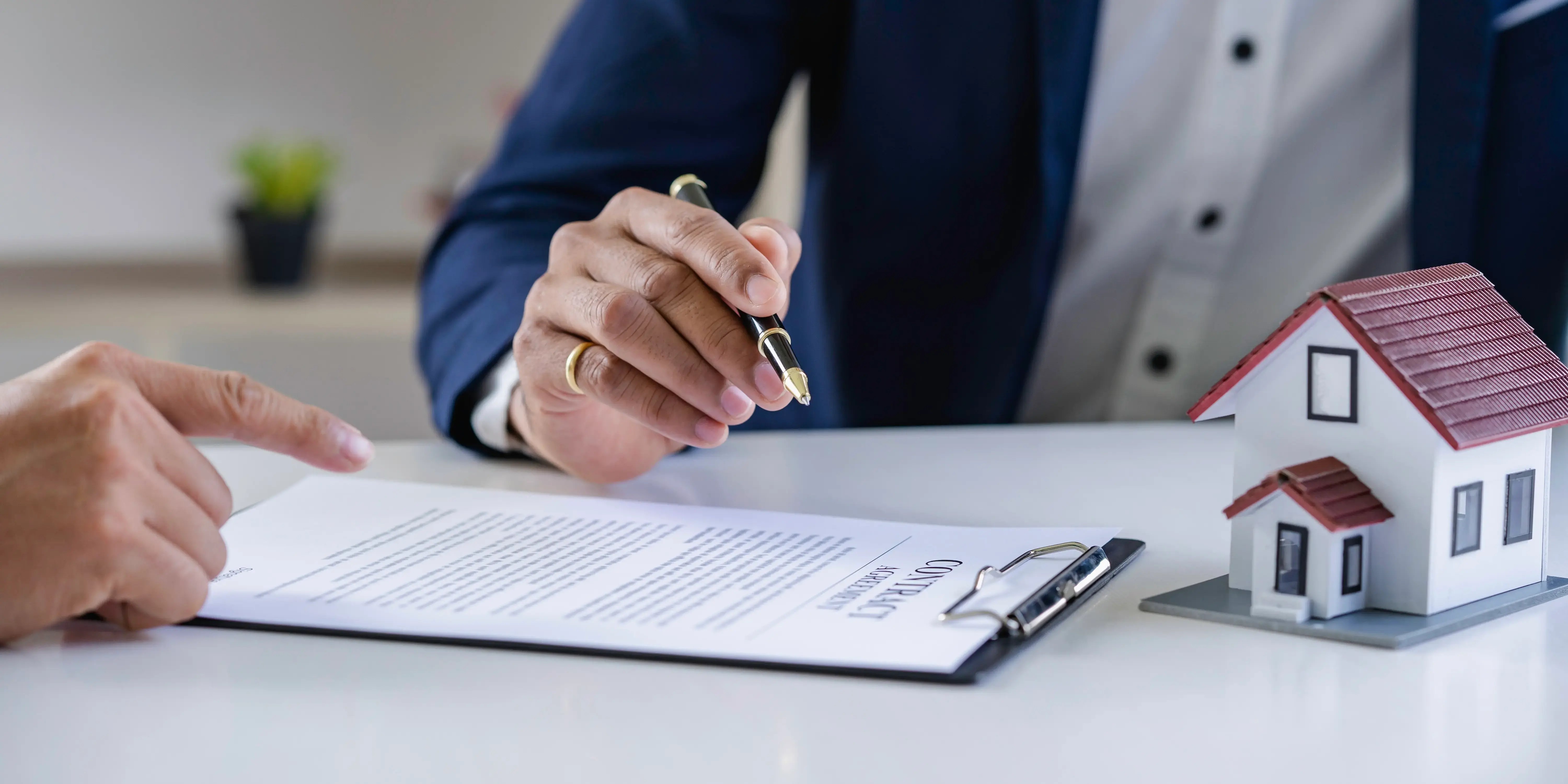 Asesor enseñándole al cliente el contrato del crédito hipotecario Cofinavit para que lo firme