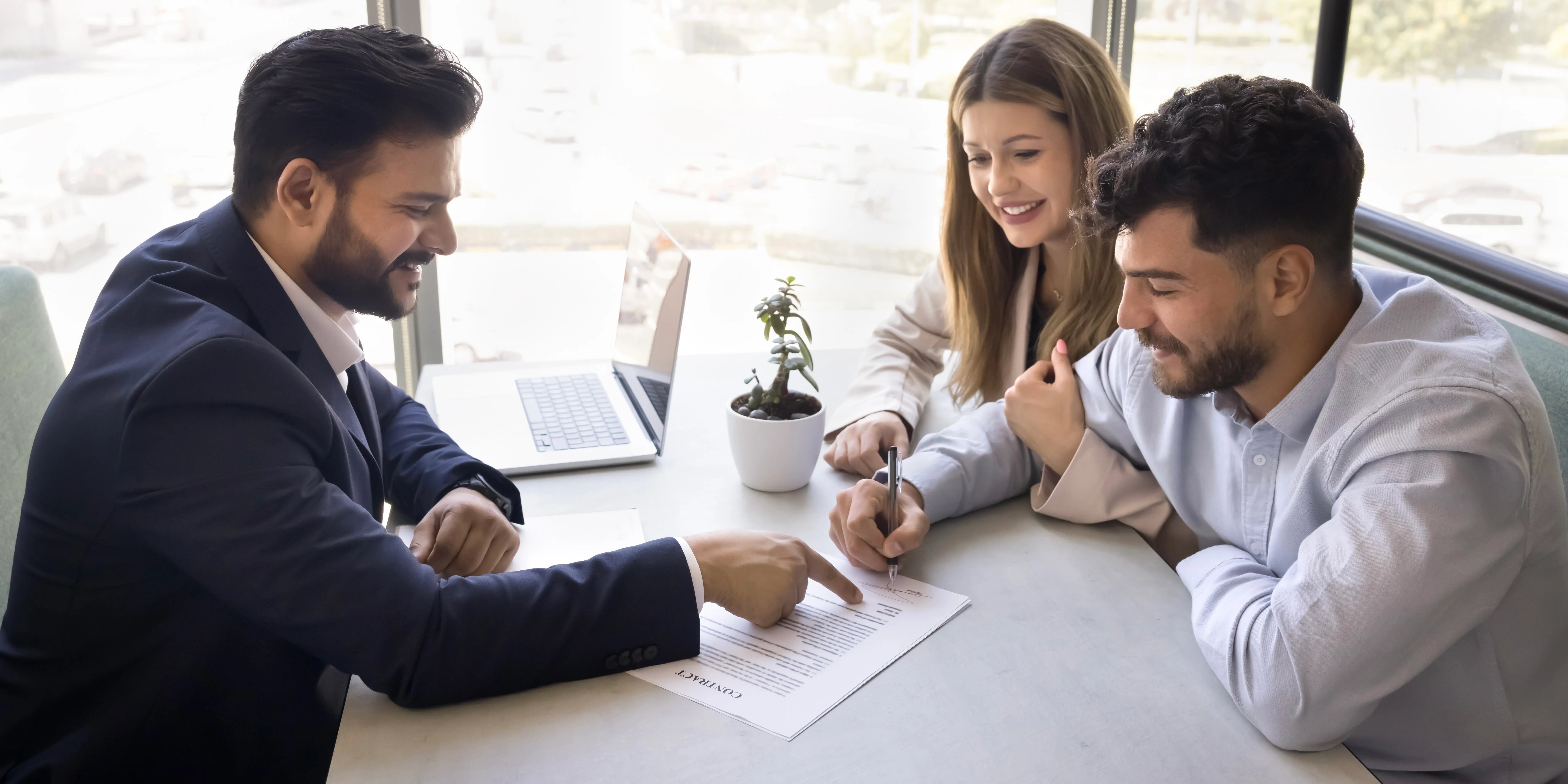 Asesor hipotecario explicando a joven pareja los diferentes tipos de créditos para comprar casa barata