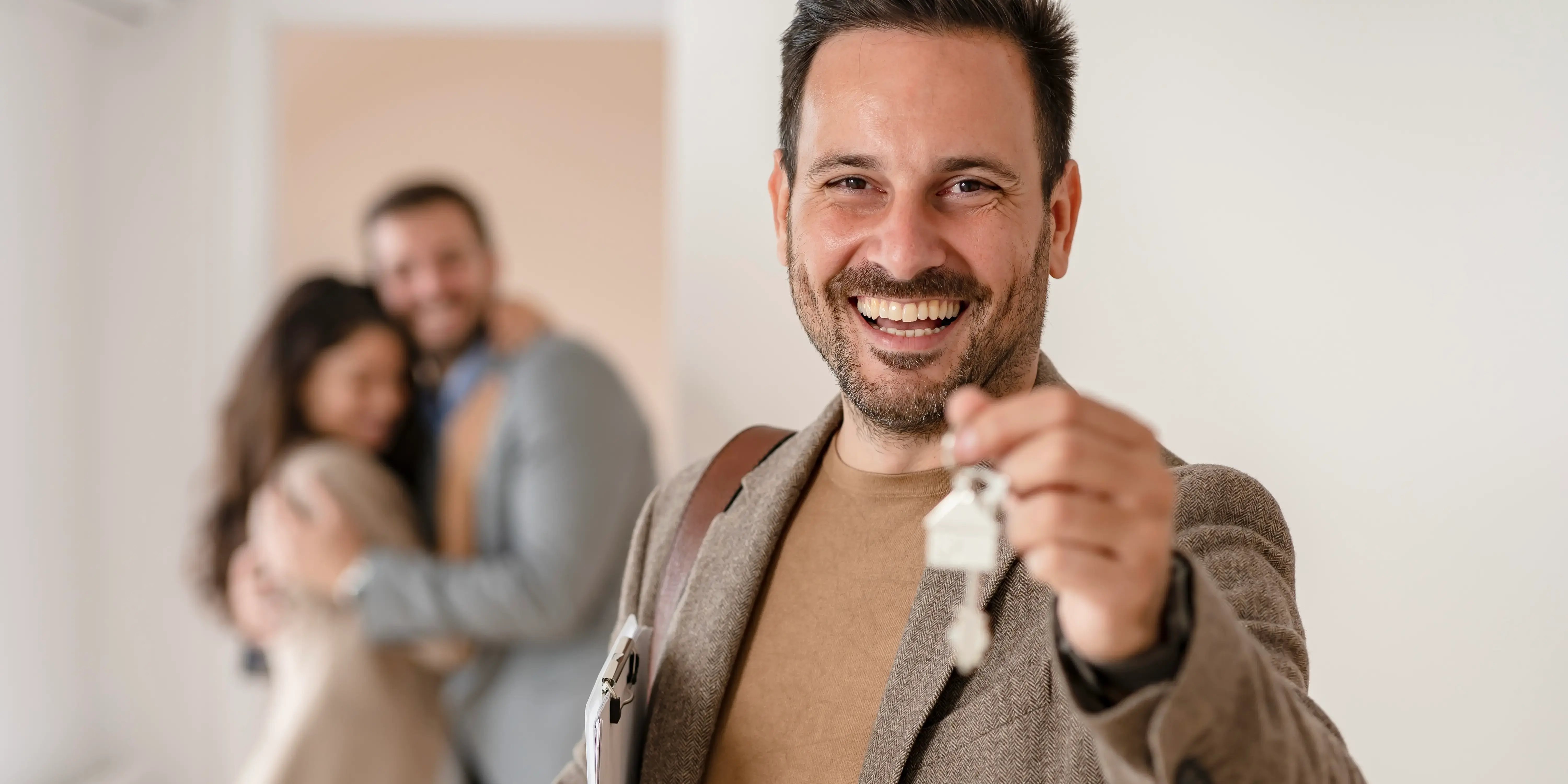 Asesor inmobiliaro sosteniendo llaves de una casa y diciéndole a una pareja los pasos clave para aprovechar las promociones inmobiliarias