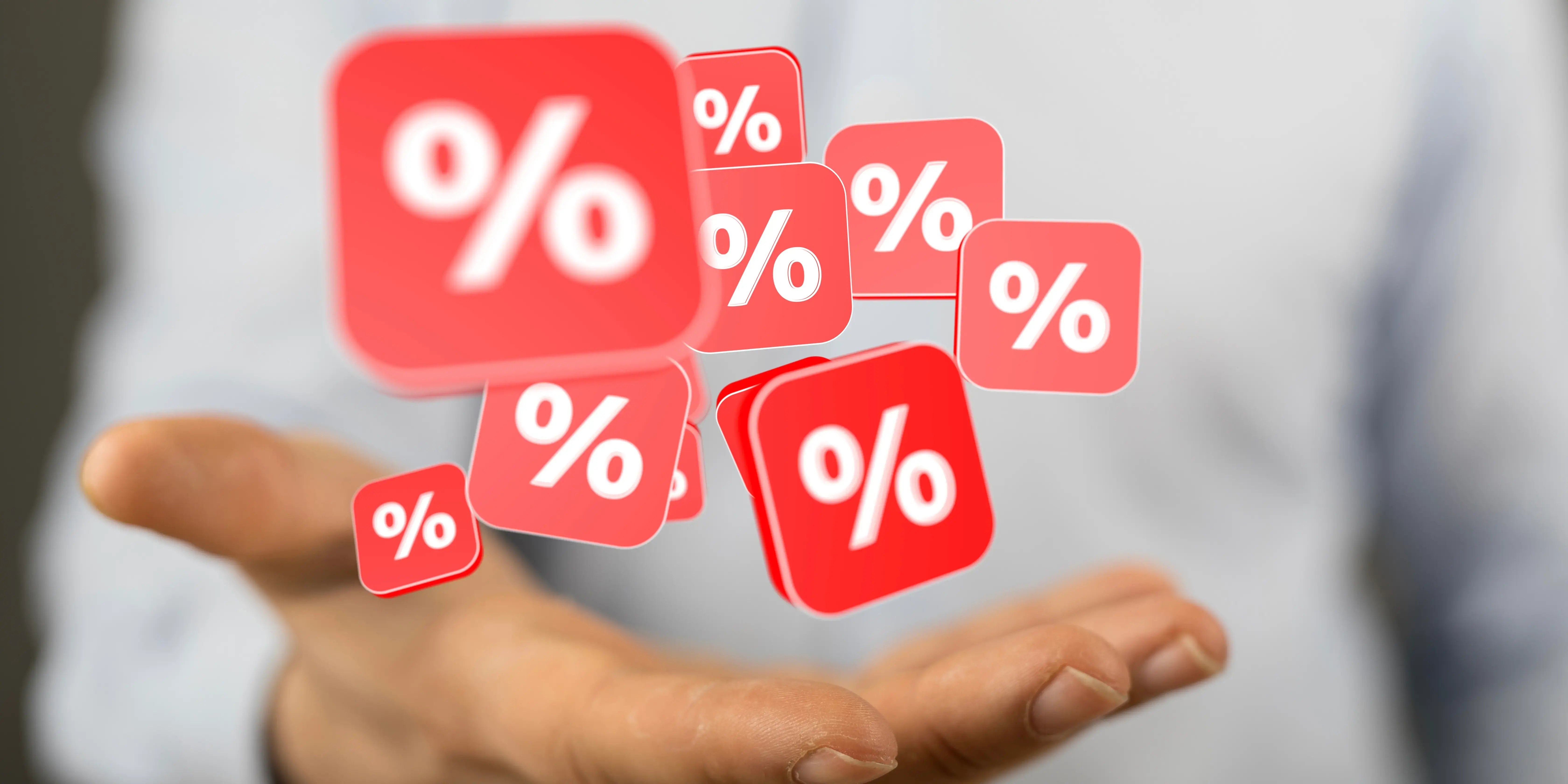 Cuadros rojos con signos de porcentaje de descuento sobre una mano por ofertas que transforman