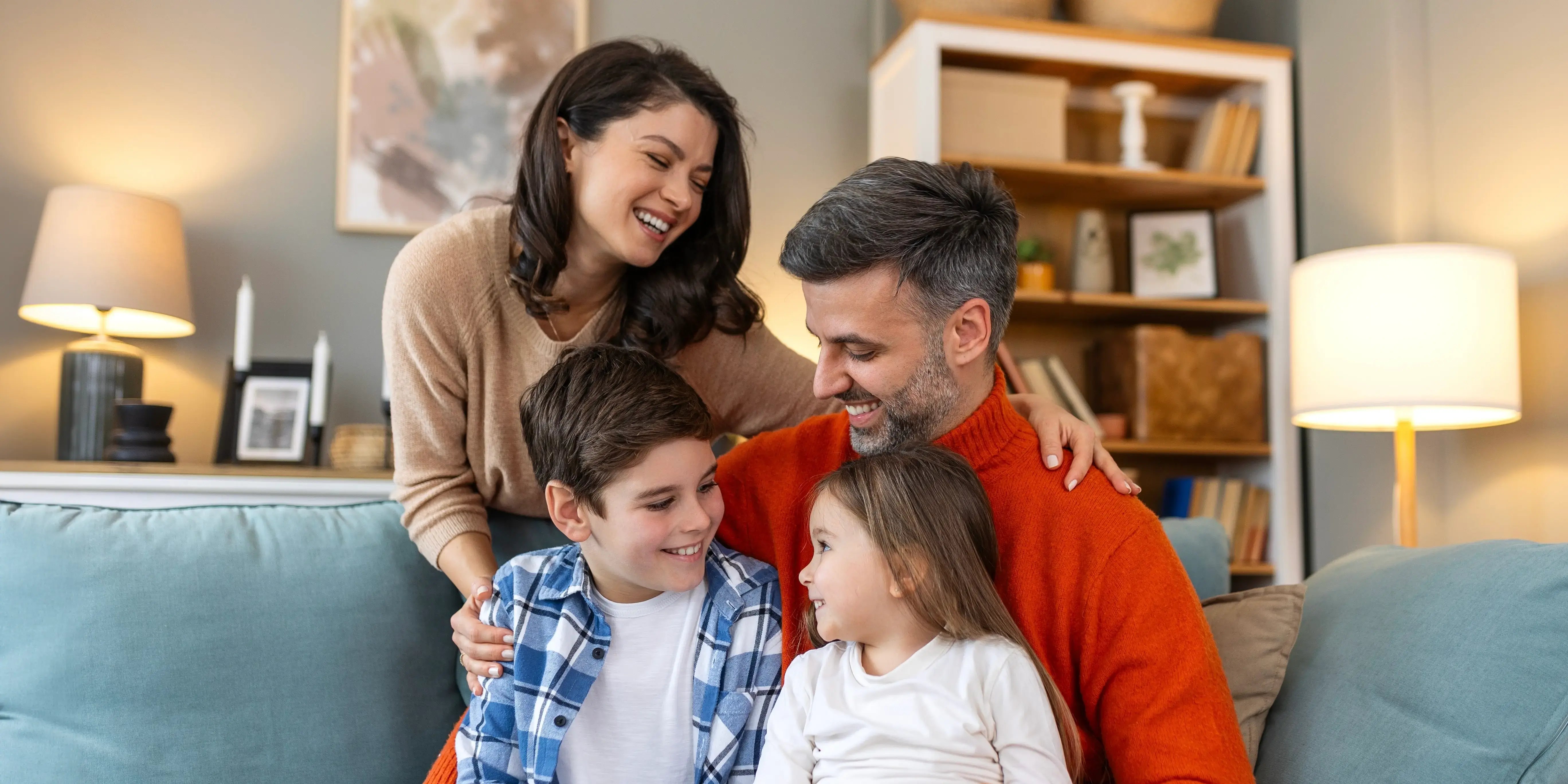 Familia feliz que se divierte en su nueva casa, se sientan en el sofá juntos