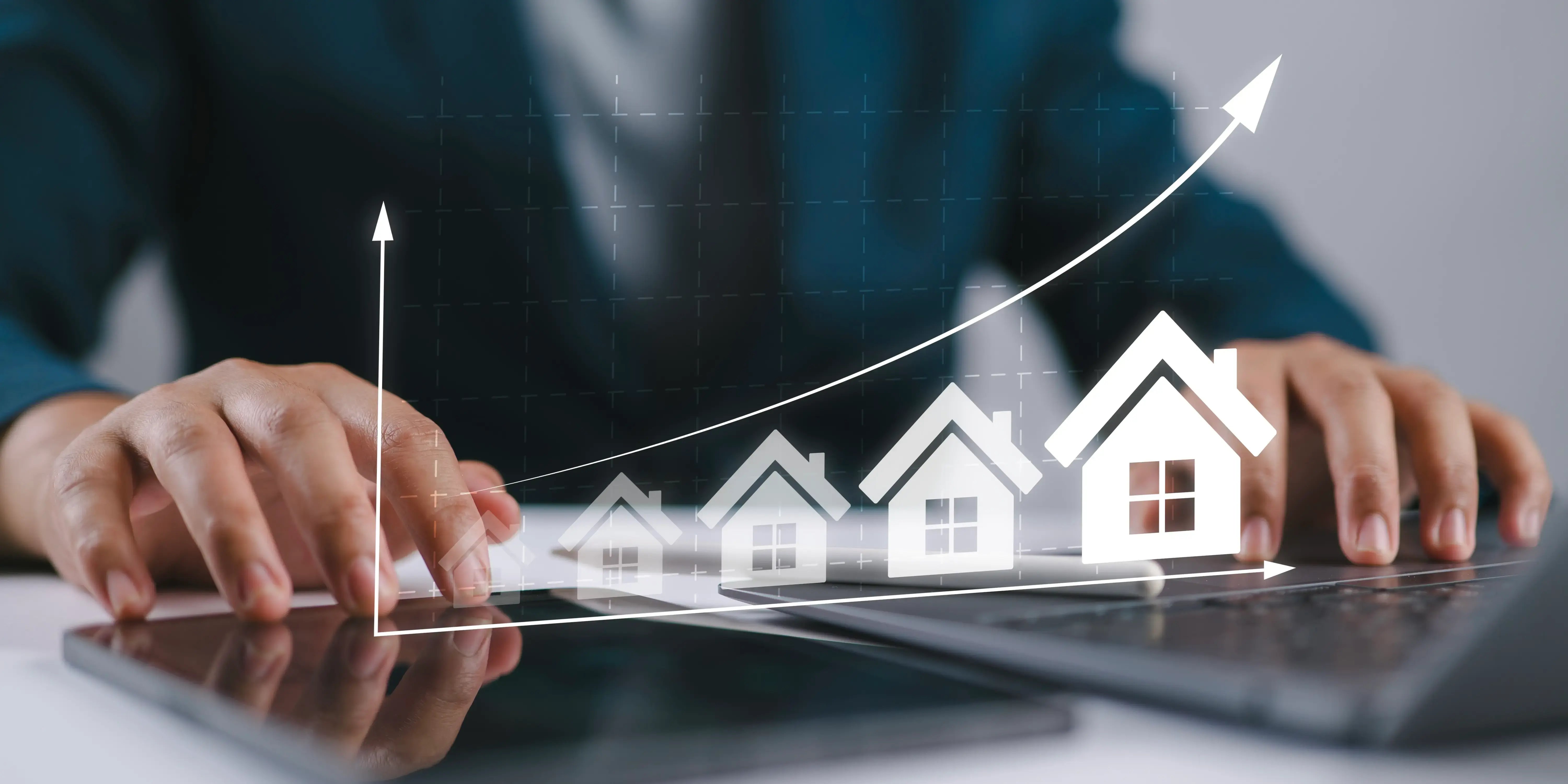 Hombre escribiendo en el teclado de la tableta con los iconos y el gráfico de la casa en ascenso, que simbolizan el crecimiento del mercado inmobiliario y cómo la plusvalía afecta la vivienda