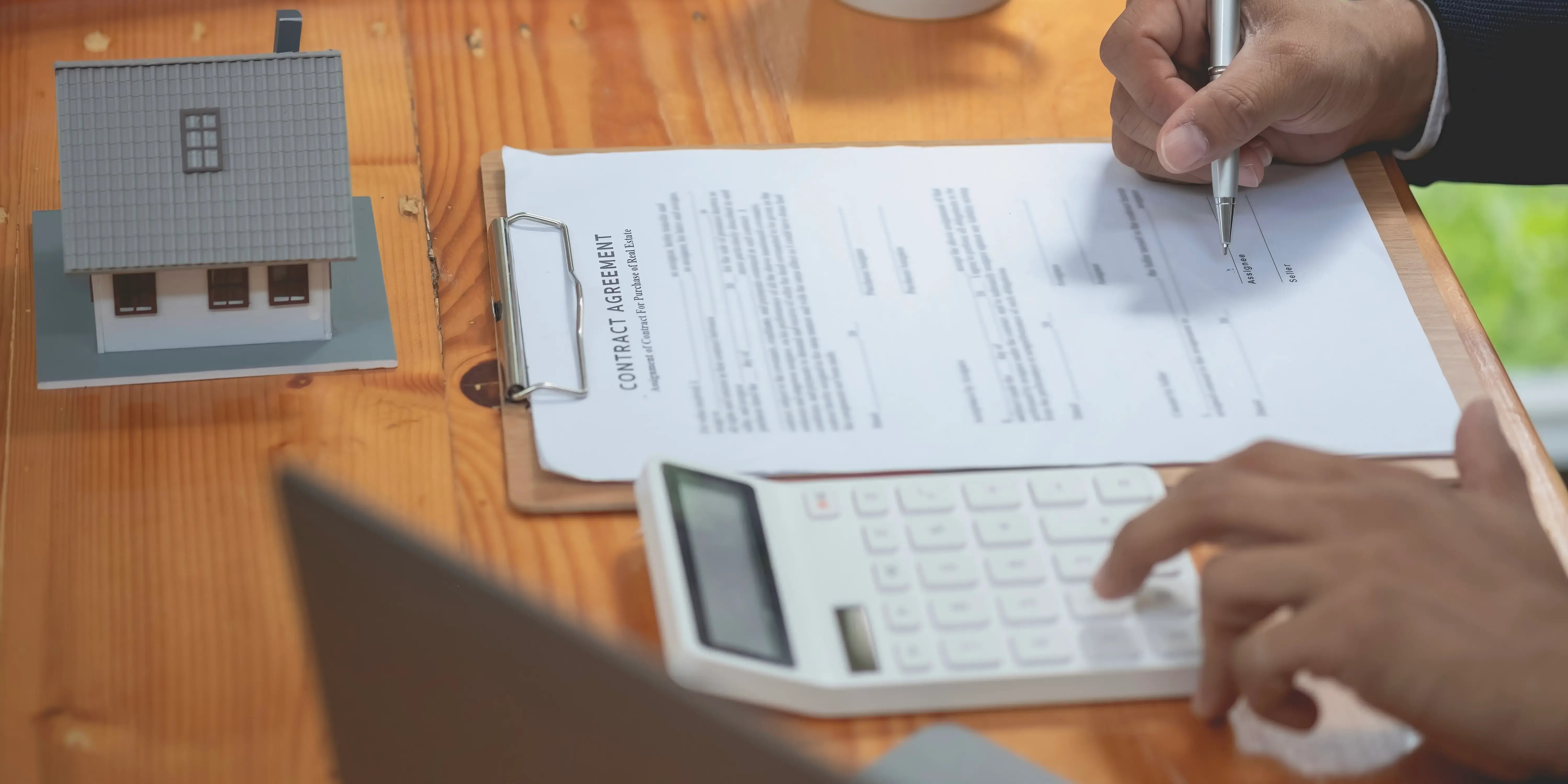 Hombre sacando cuentas en una calculadora para calcular los gastos adicionales y firmar el contrato de compraventa para comprar casa