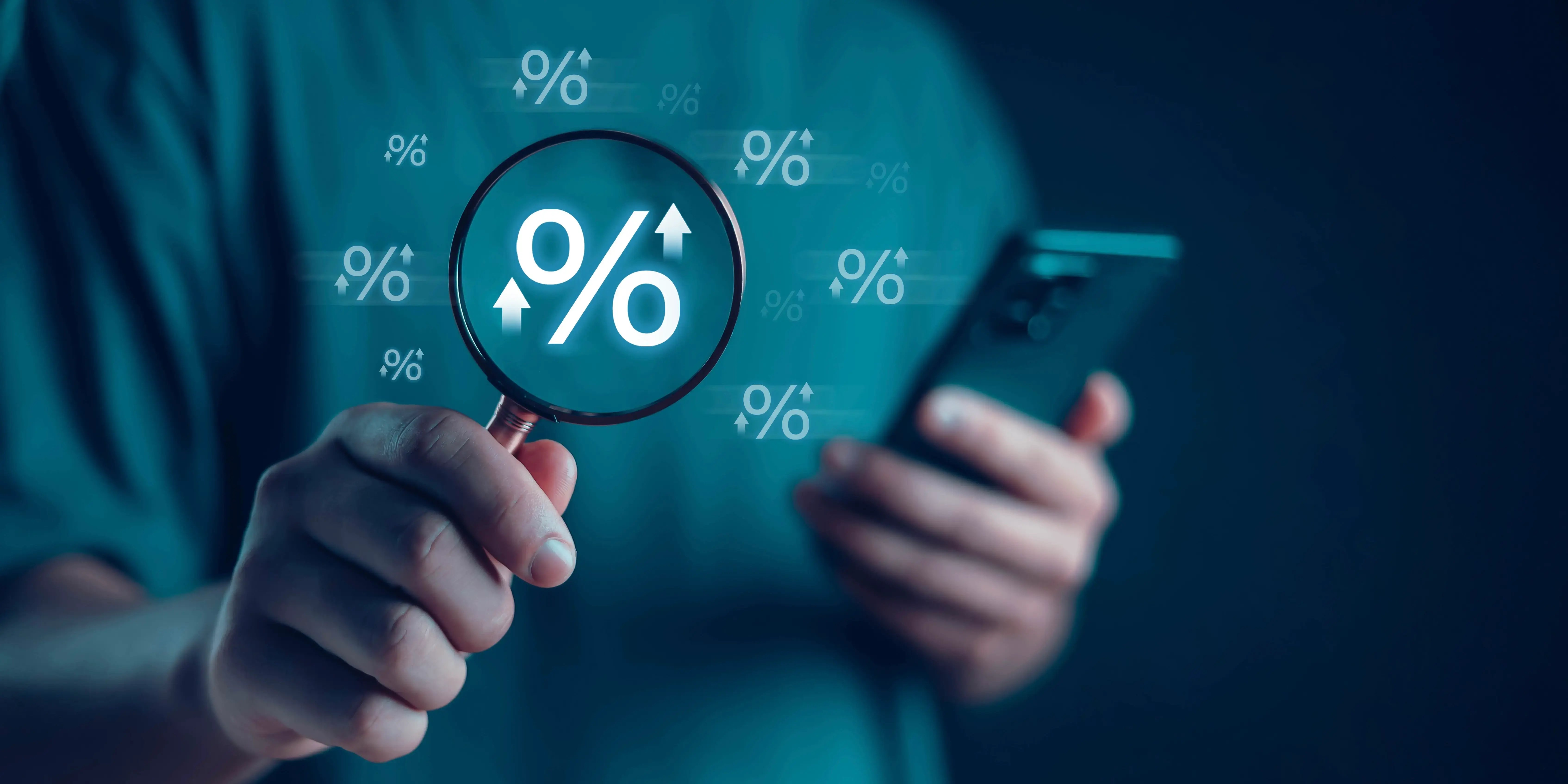Hombre sosteniendo una lupa y un smatphone comparando tasas de interés para conocer las opciones de intereses pagados por anticipado