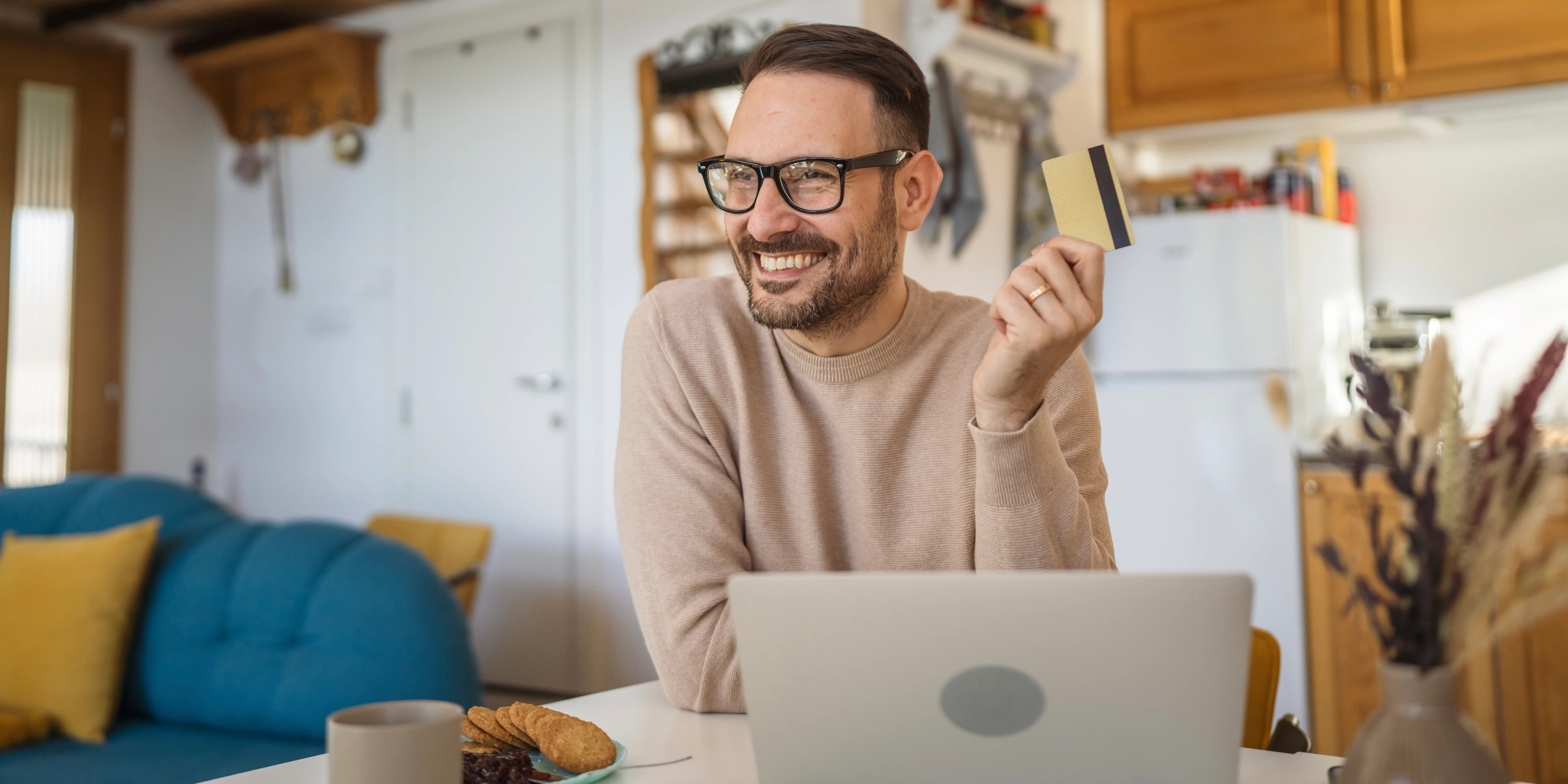 Hombre sosteniendo una tarjeta de crédito y viendo en una computadora los diferentes tipos de crédito