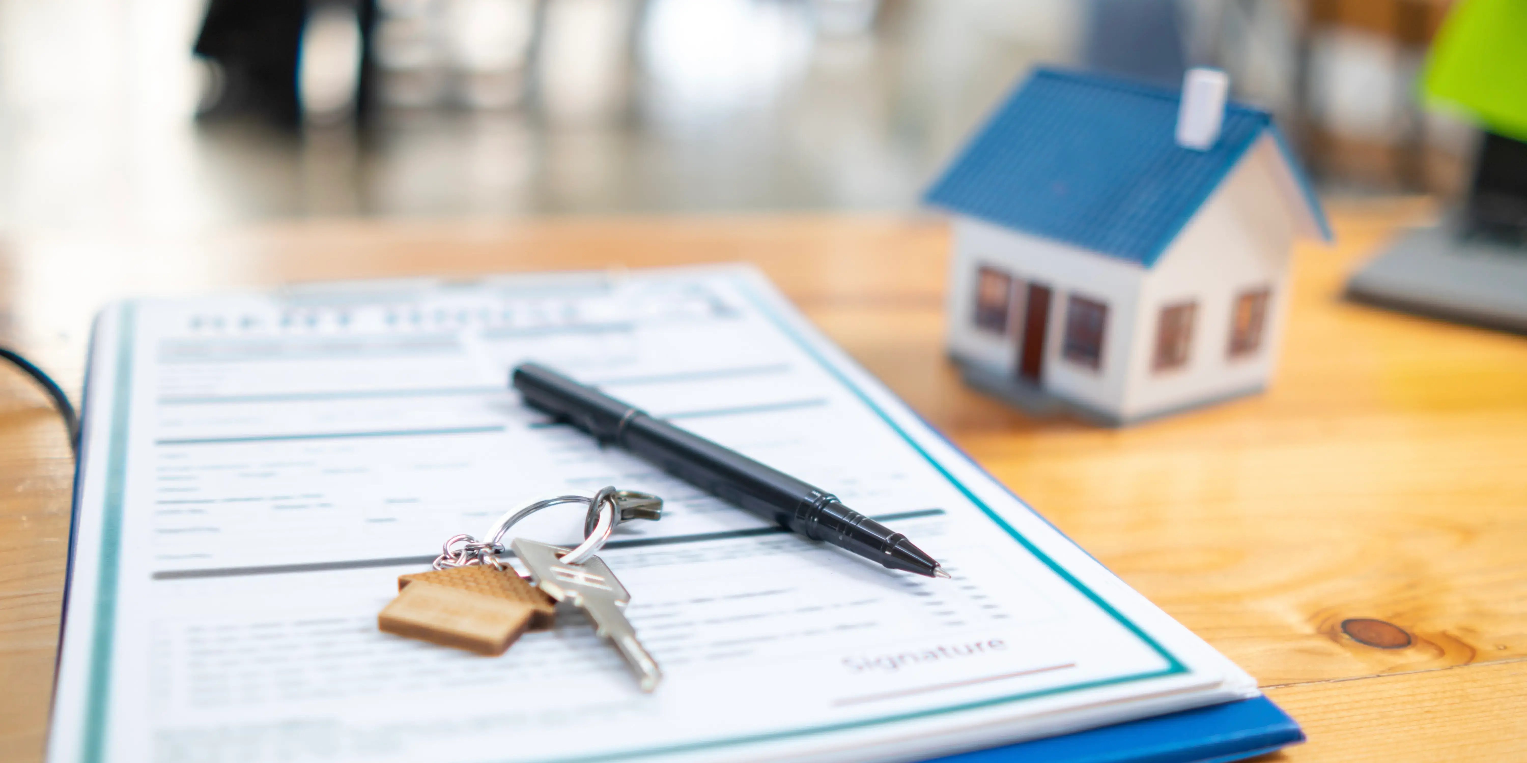 Llaves, pluma y documentos encima de un escritorio con los requisitos para solicitar crédito hipotecario