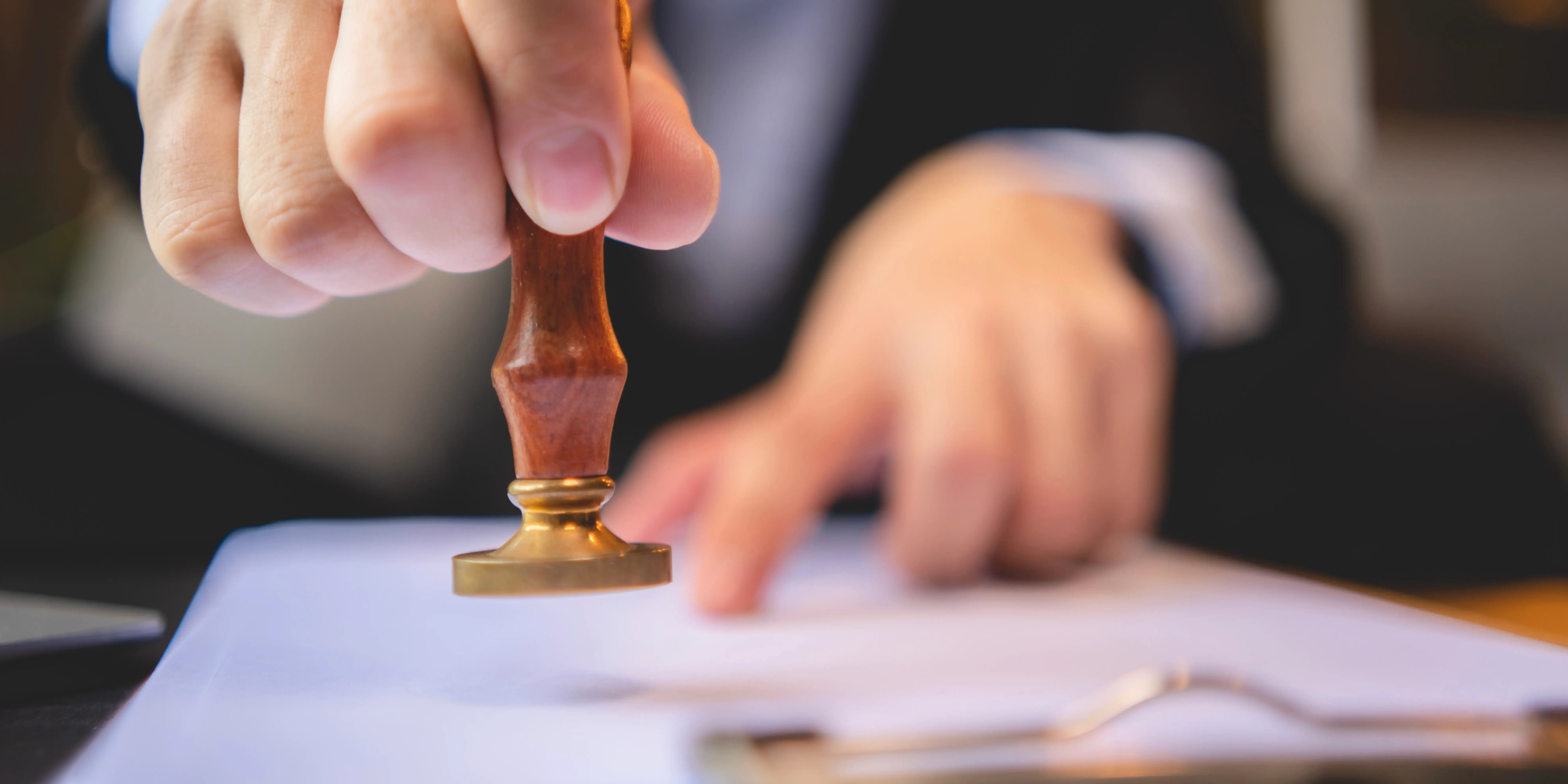Mano de notario público colocando sello en los documentos aprobados de escrituración de una casa