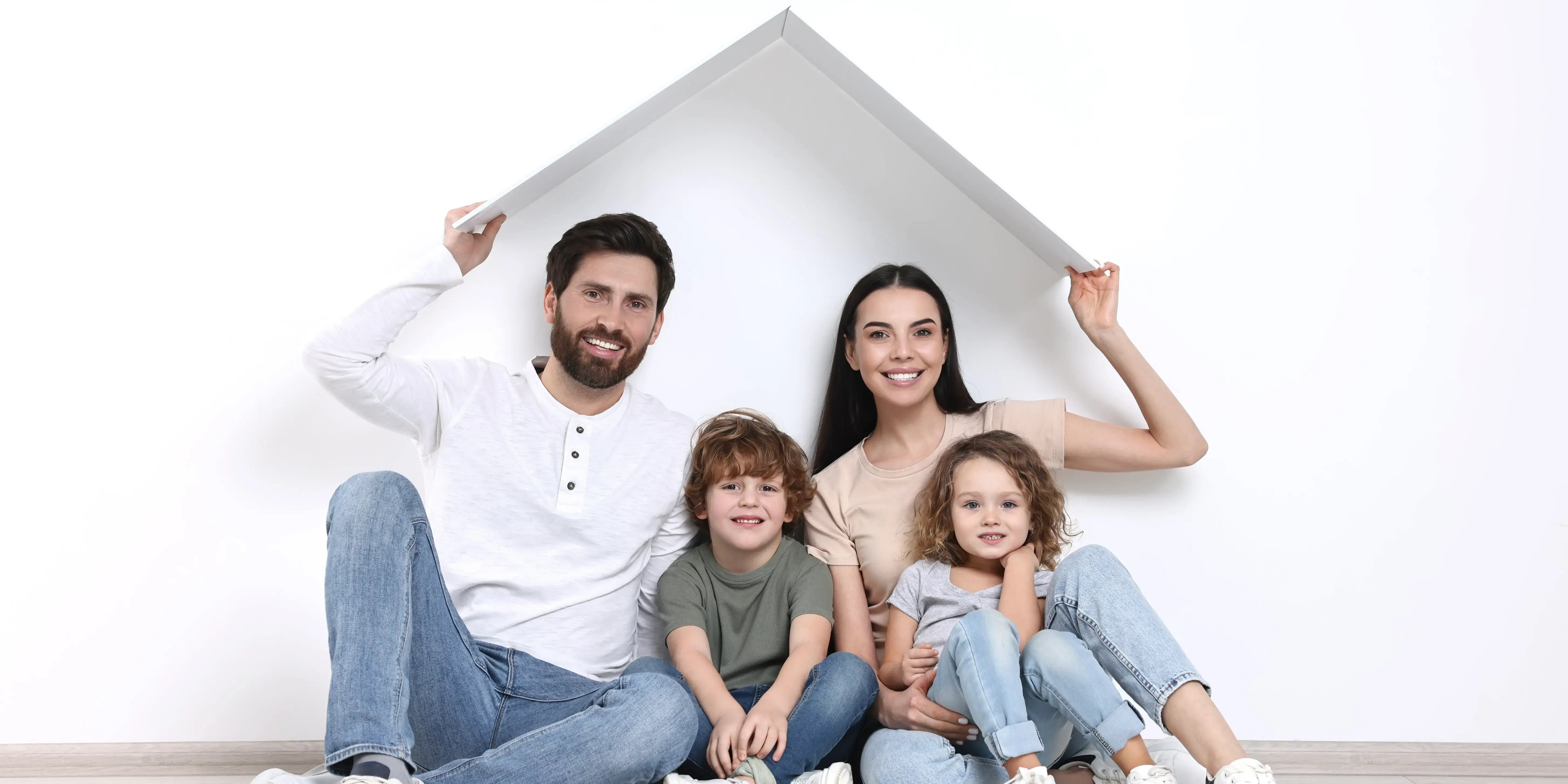 Mujer feliz y su marido sosteniendo el techo de plástico mientras se sienta con los niños en el suelo en casa en una zona residencial