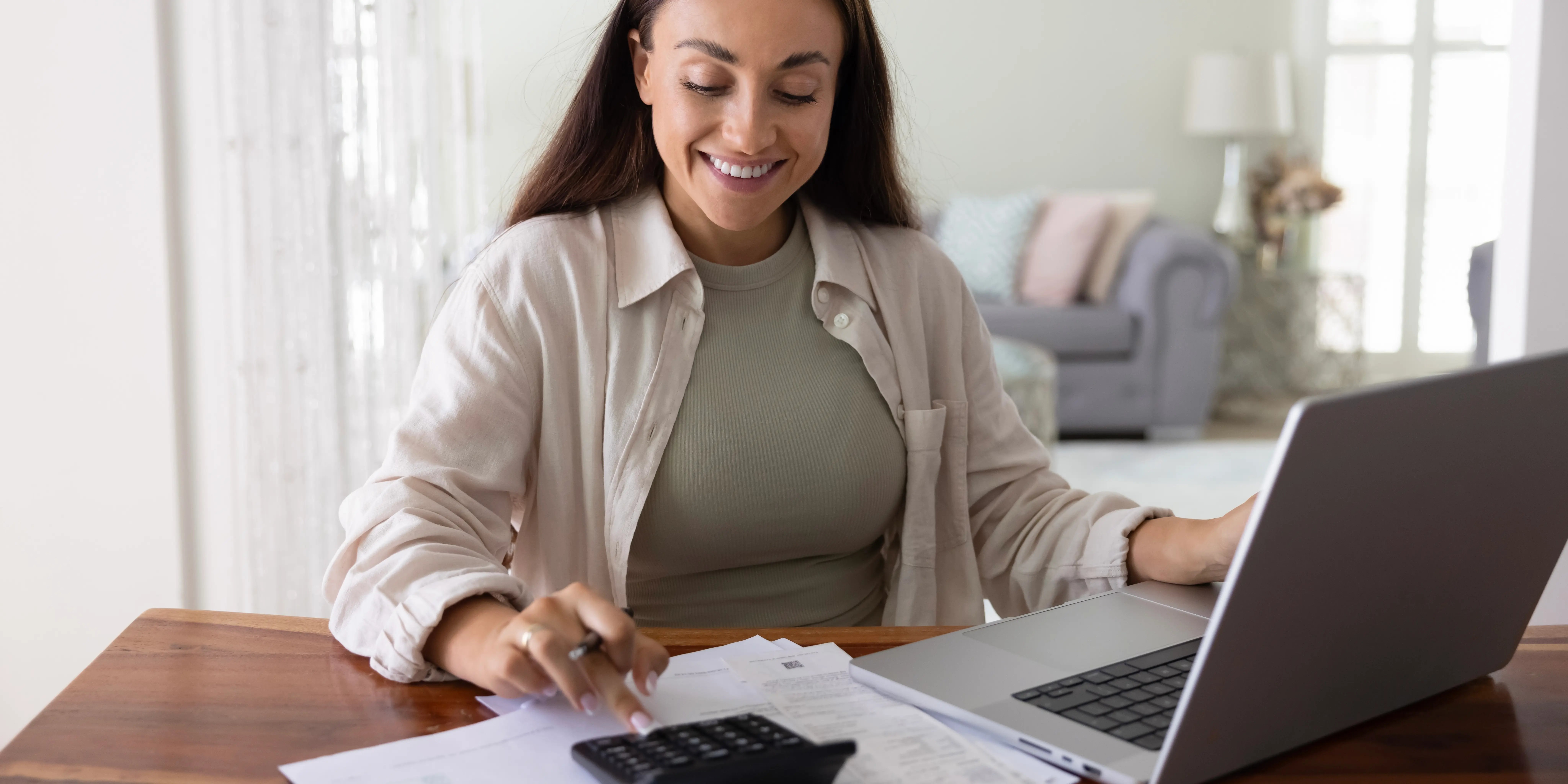 Mujer sonriendo utilizando una calculadora sacando el porcentaje del factor de descuento Infonavit
