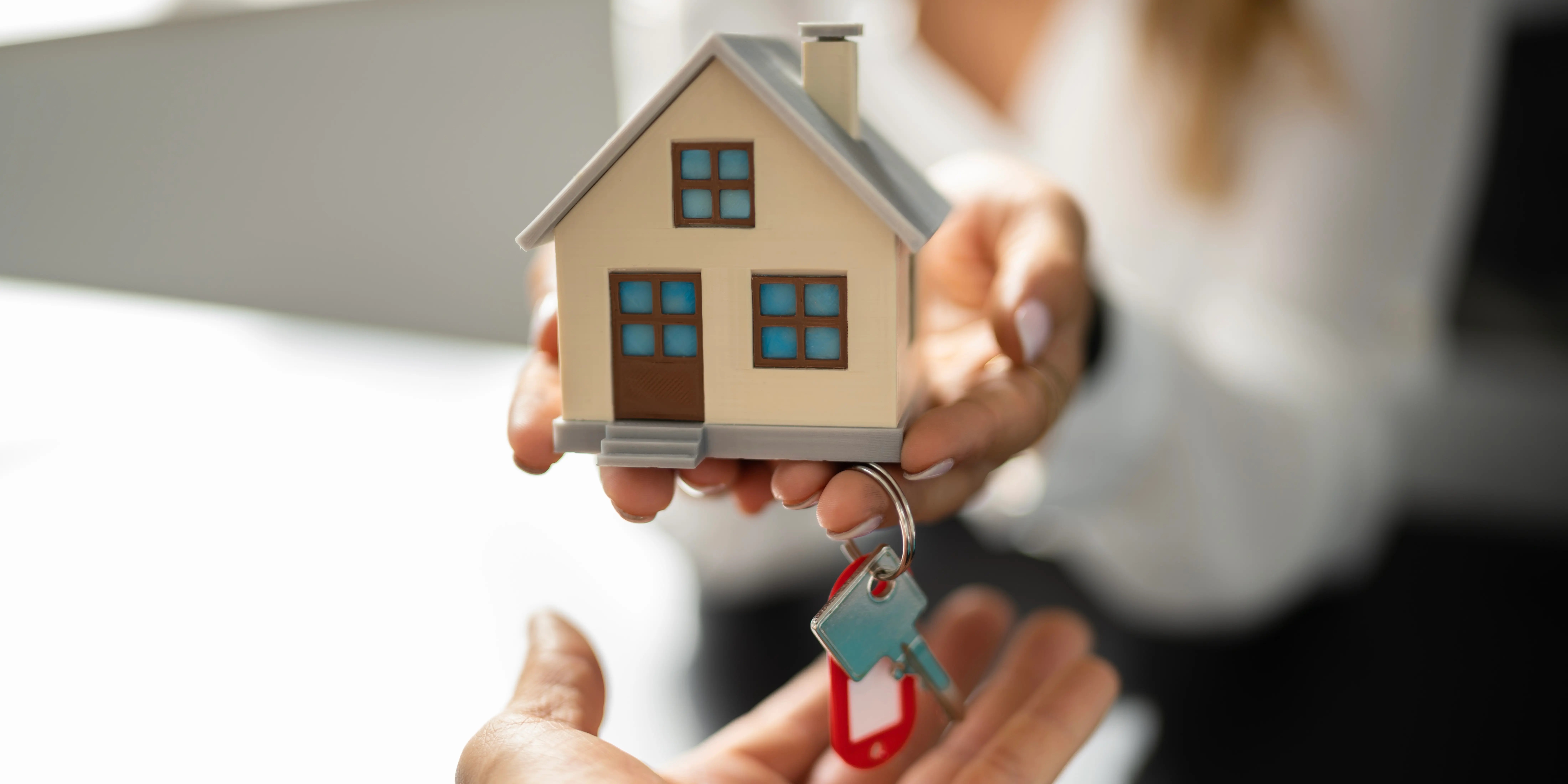 Mujer sosteniendo una casa de madera y unas llaves para entregárselas al propietario por la liberación de hipoteca Infonavit -1