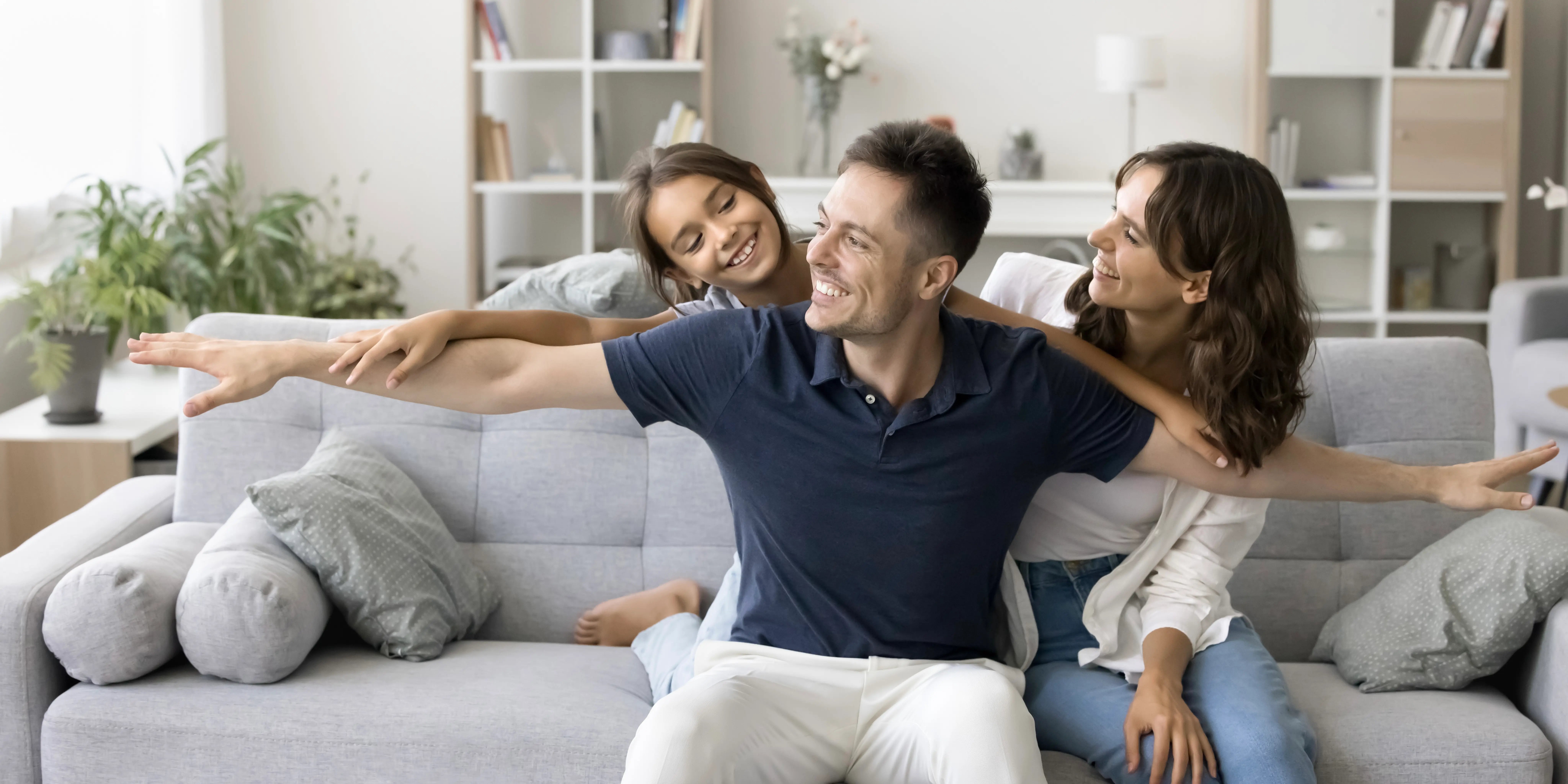 Padres e hija sonriendo en la sala de su casa, familia segura con la tenencia de su casa y sea una vivienda adecuada
