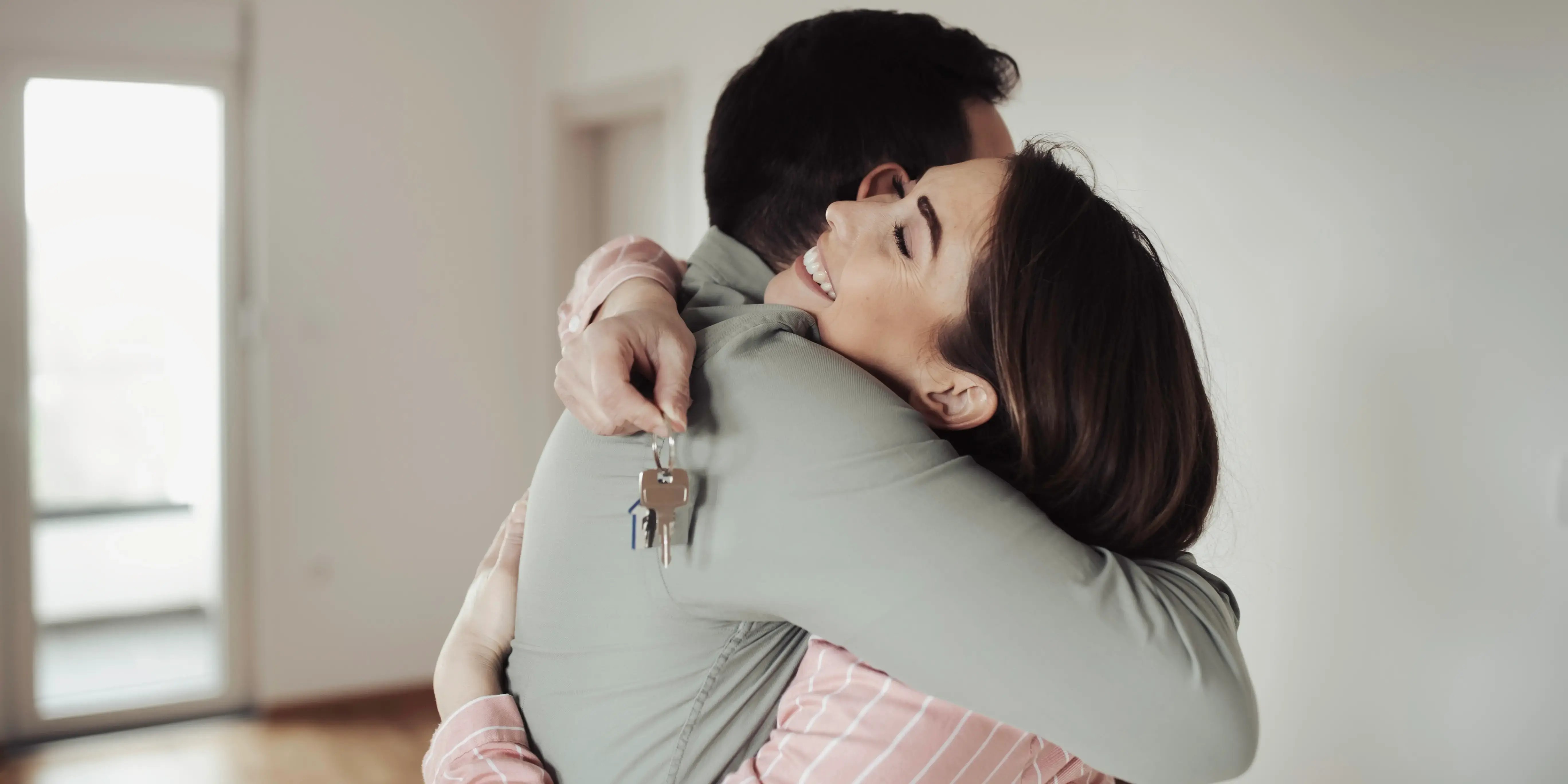 Pareja abrazándose y sosteniendo unas llaves estrenando casa usando el crédito conyugal FOVISSSTE