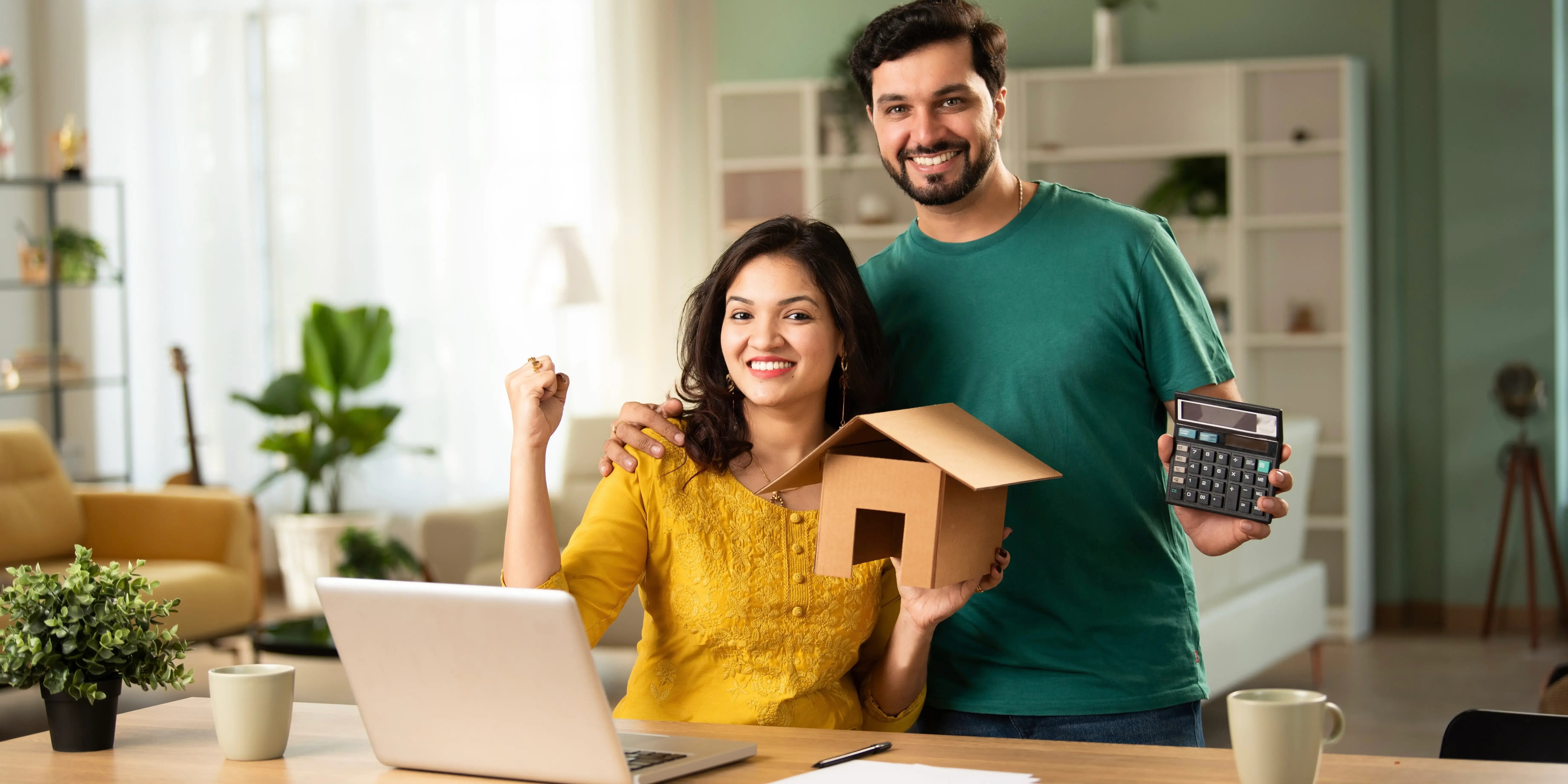 Pareja con una computadora y una calculadora haciendo cuentas para comprar casa con bajo presupuesto