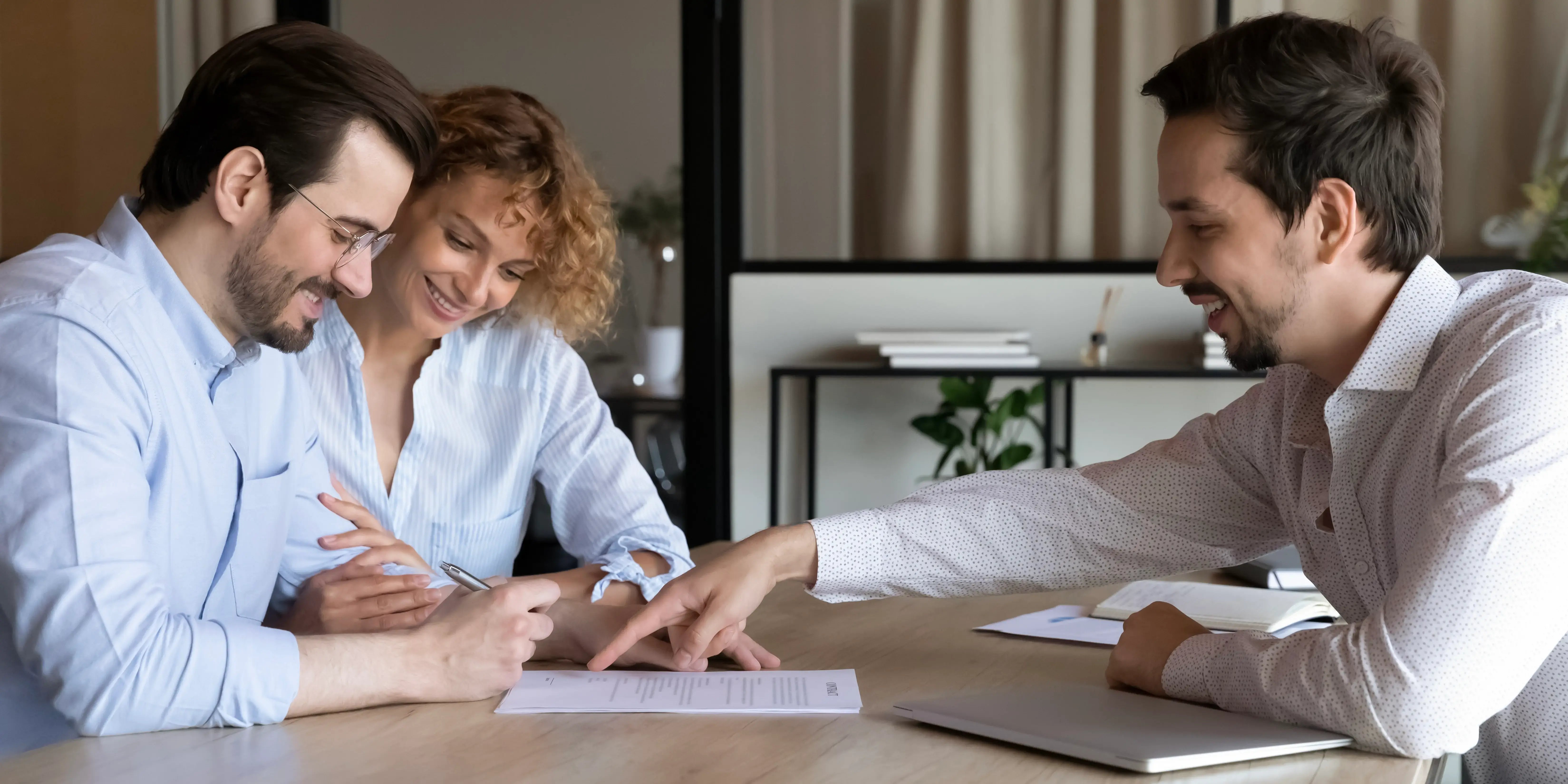 Pareja junto con un asesor viendo los requisitos para solicitar un subsidio gubernamental para comprar casa