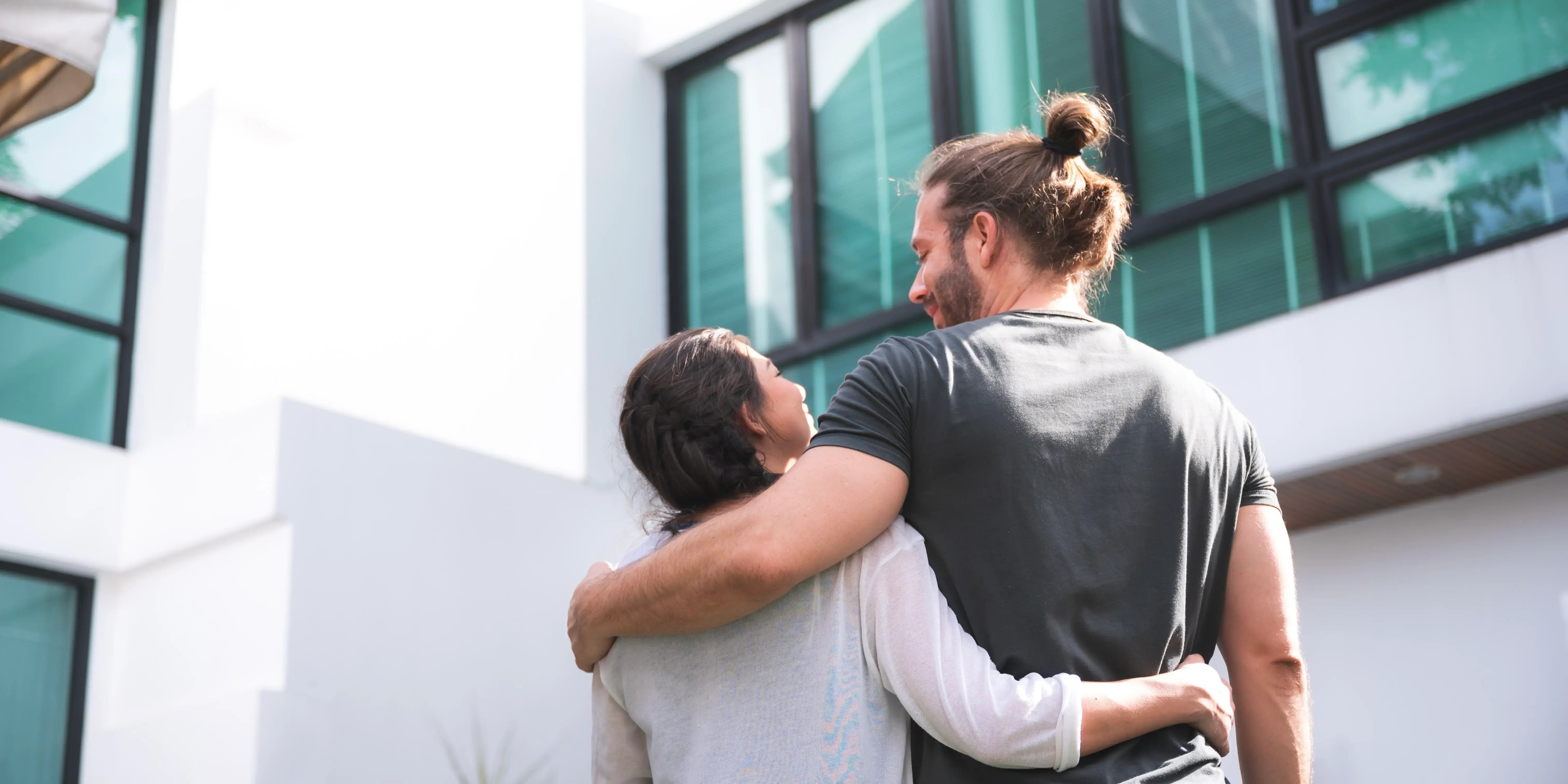 Pareja viendo por fuera la fachada de una vivienda para comprar casa