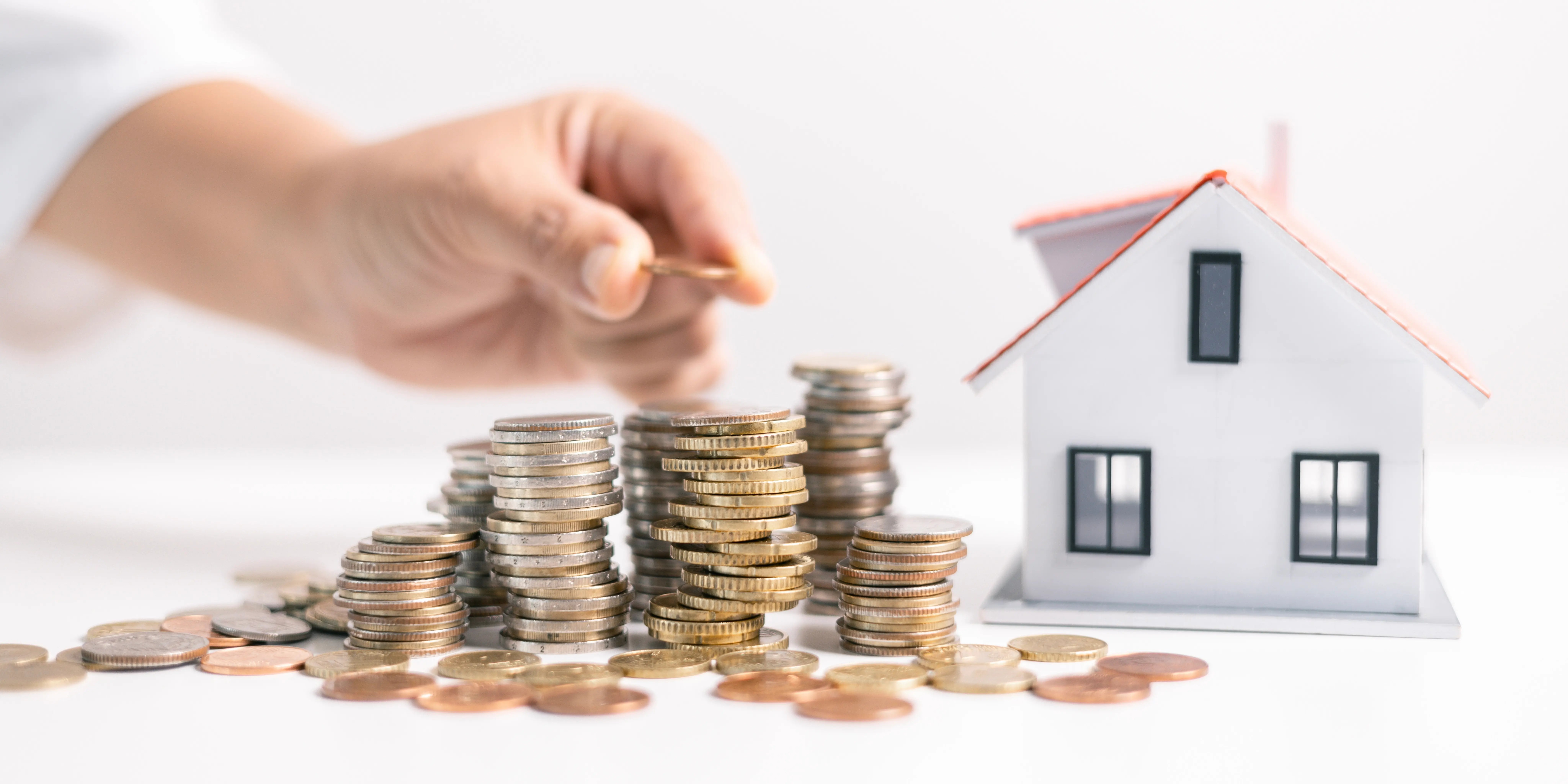 Persona colocando monedas y acomodádolas en pequeñas torres para aprovechar el programa Nivela tu pago Infonavit