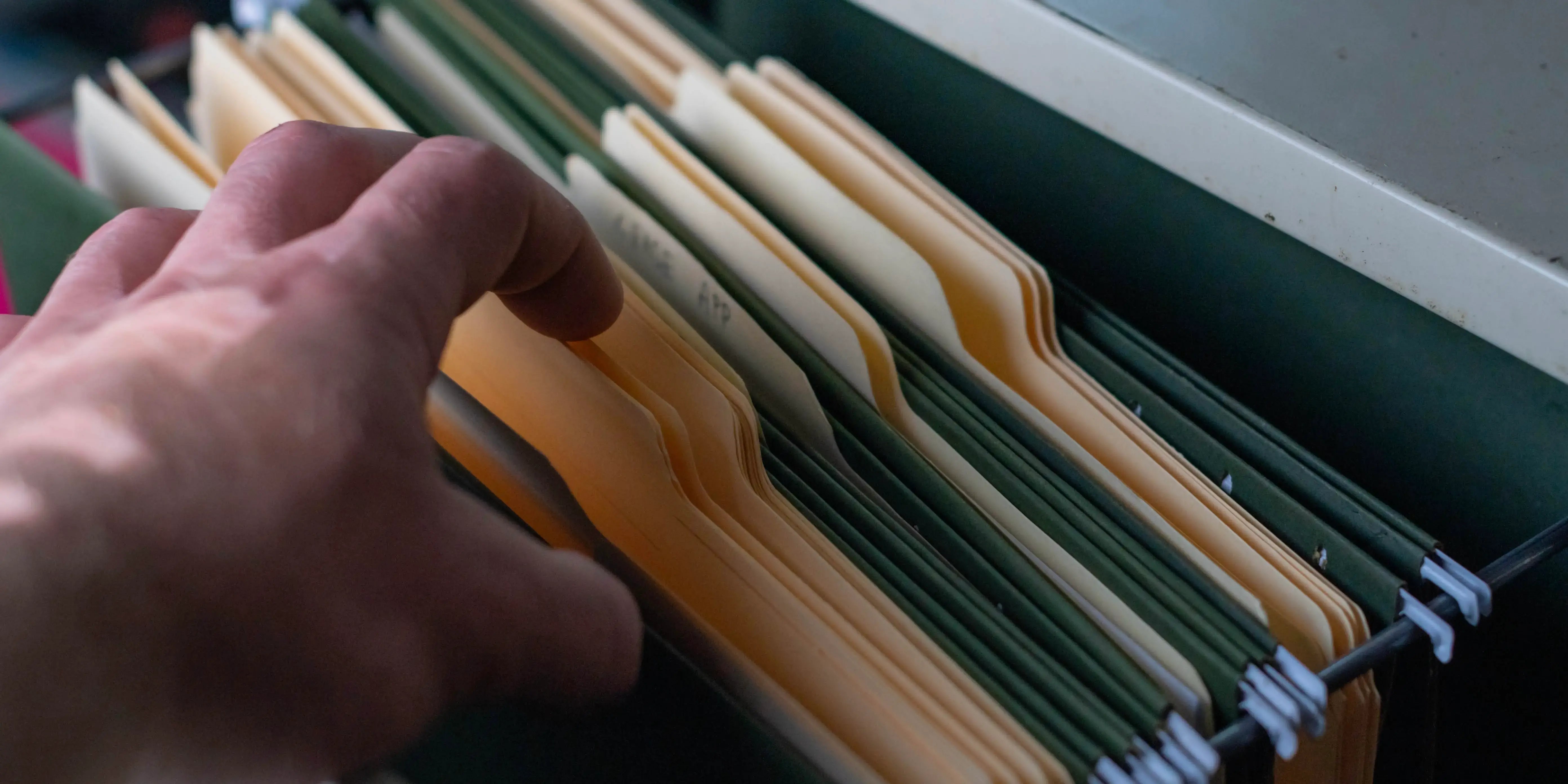 Persona guardando en folders los documentos de la carta de liberación de la hipoteca, el aviso de suspensión y el comprobante de cancelación