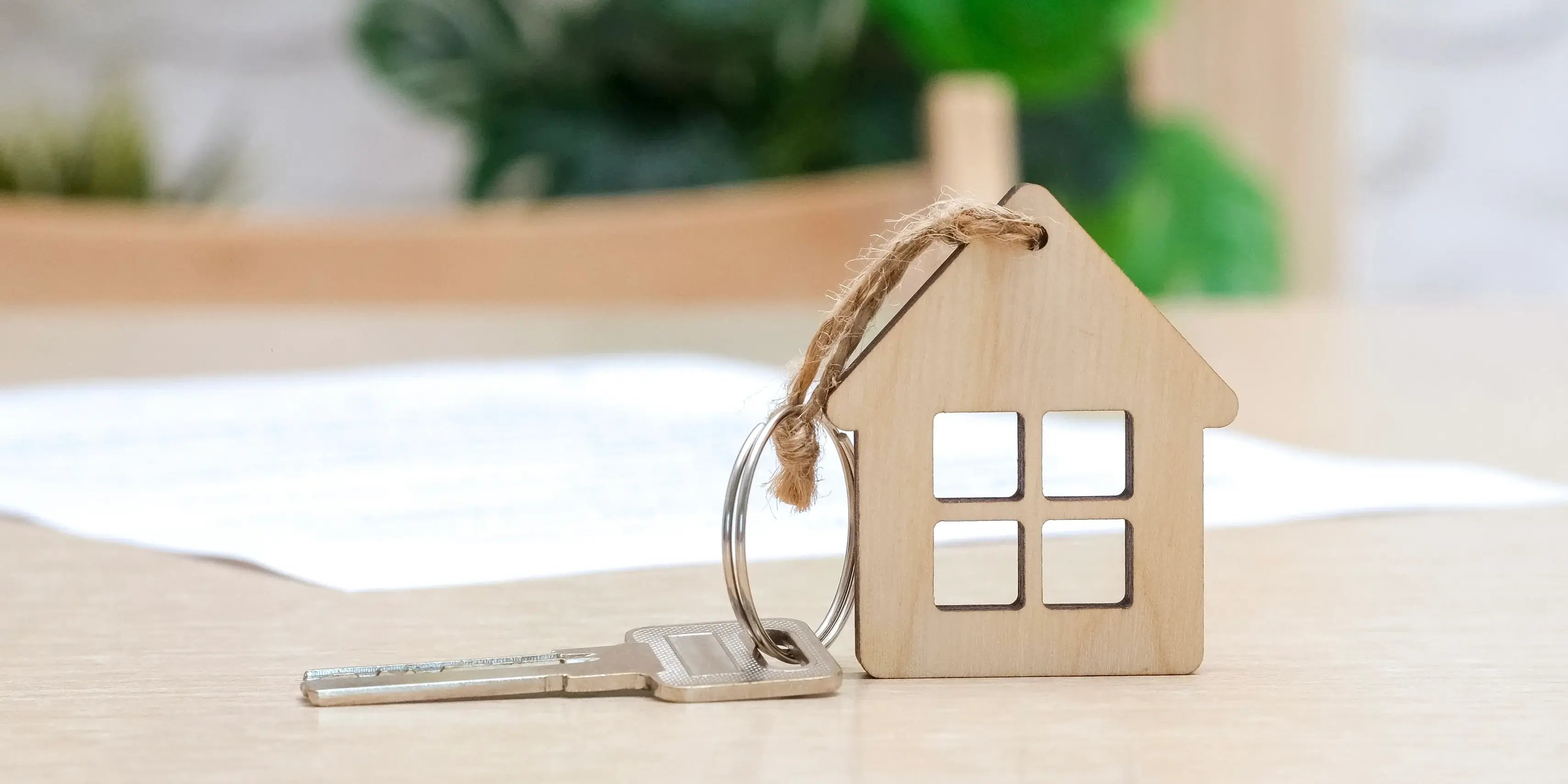 Sobre una mesa se encuentra una llave con llavero en forma de casa y la hoja de retención Infonavit