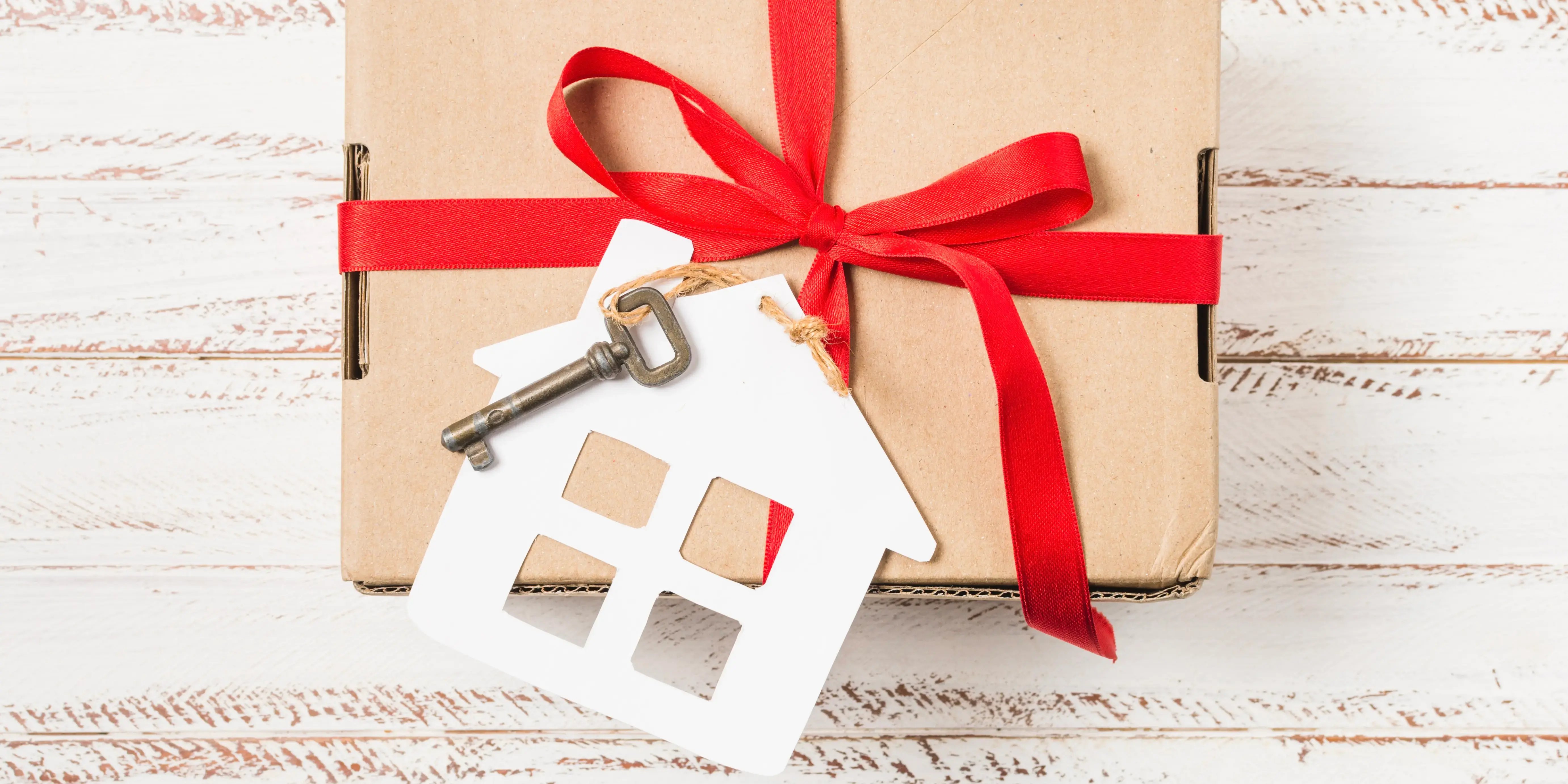 Caja de regalo con listón rojo y una llave. Crédito hipotecario