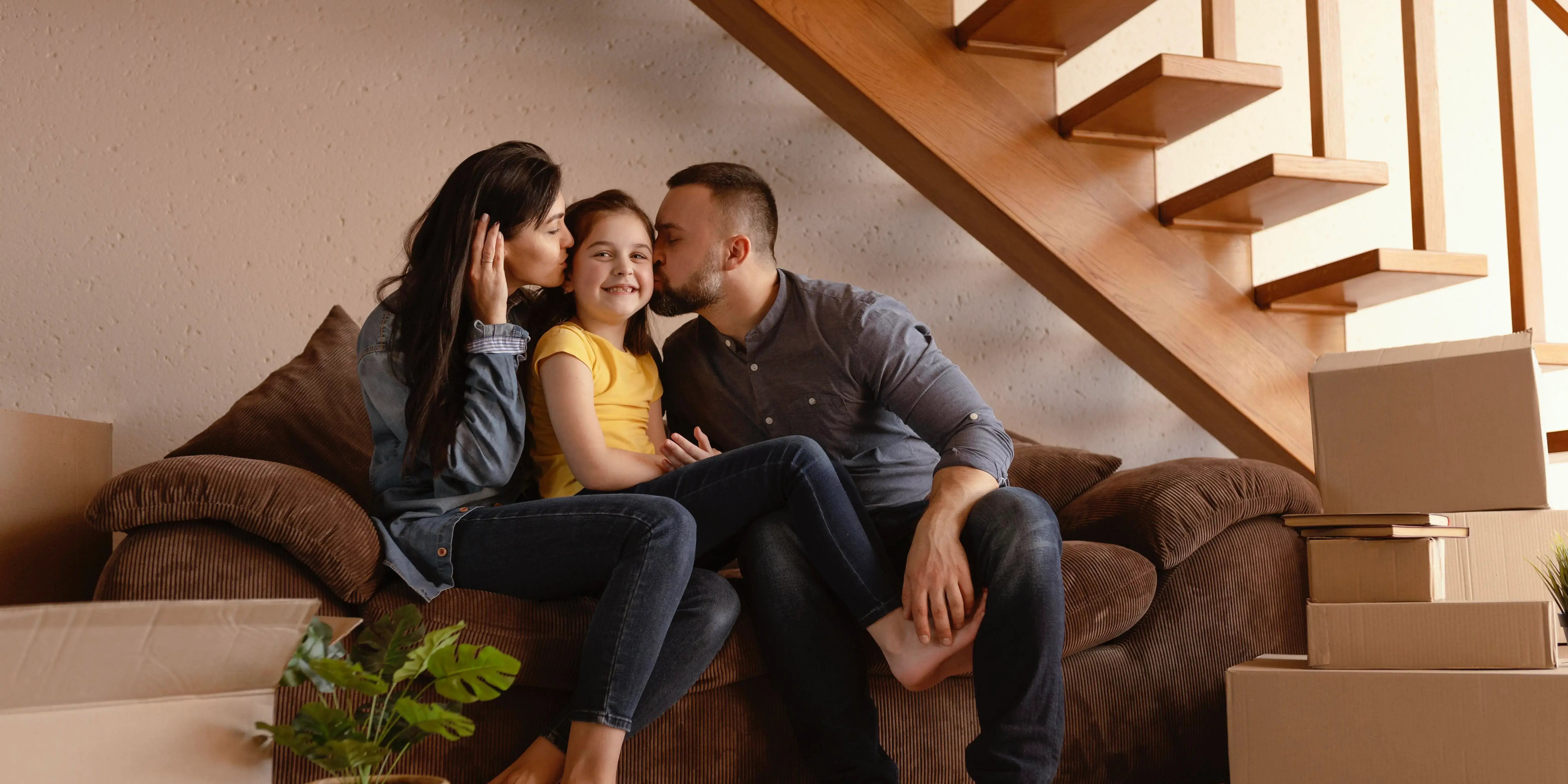 familia sentada en sillón abajo de la escalera. beneficios de vivir en una casa dúplex