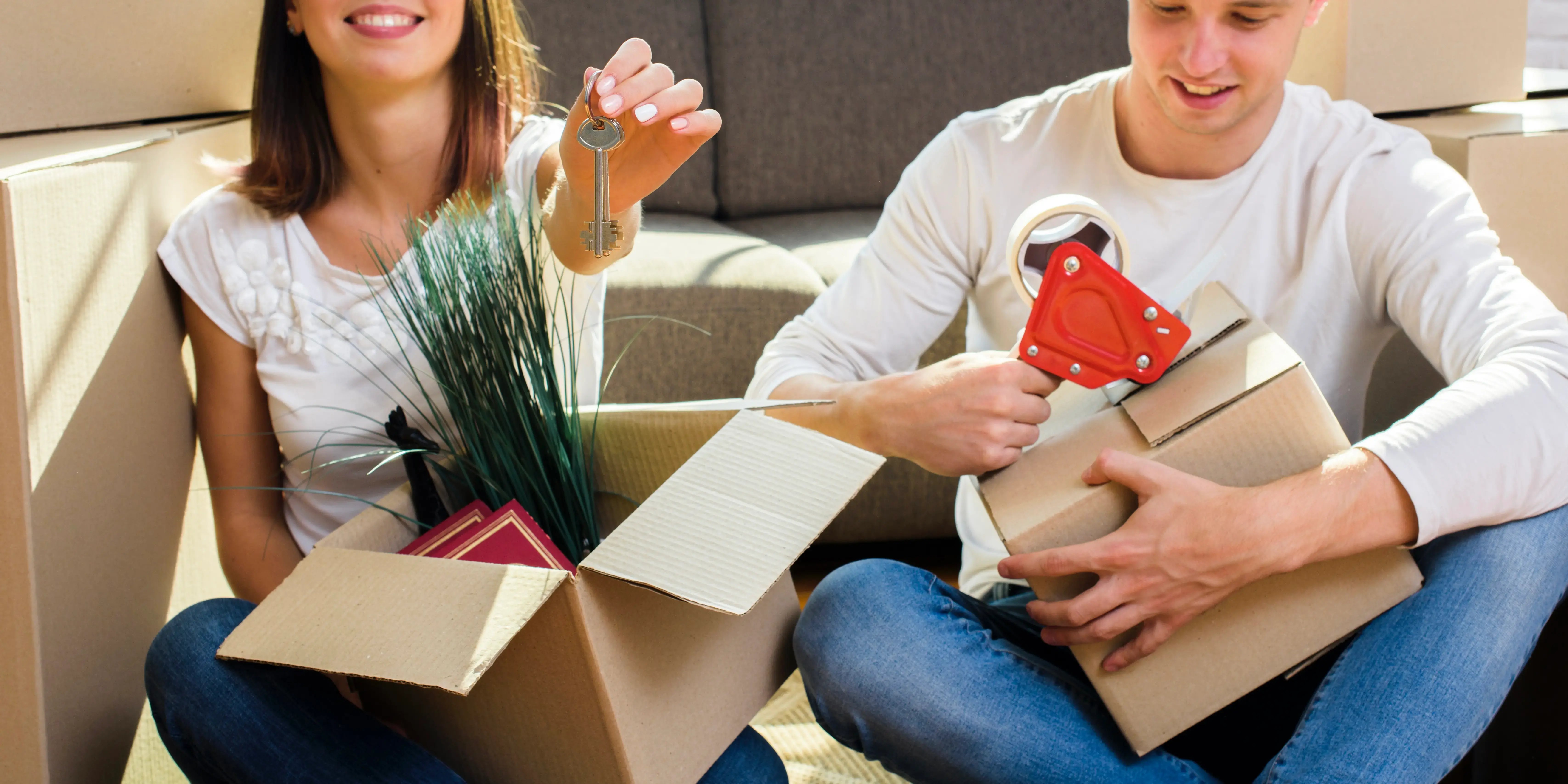 Pareja con cajas de mudanza y unas llaves. Propósito comprar casa