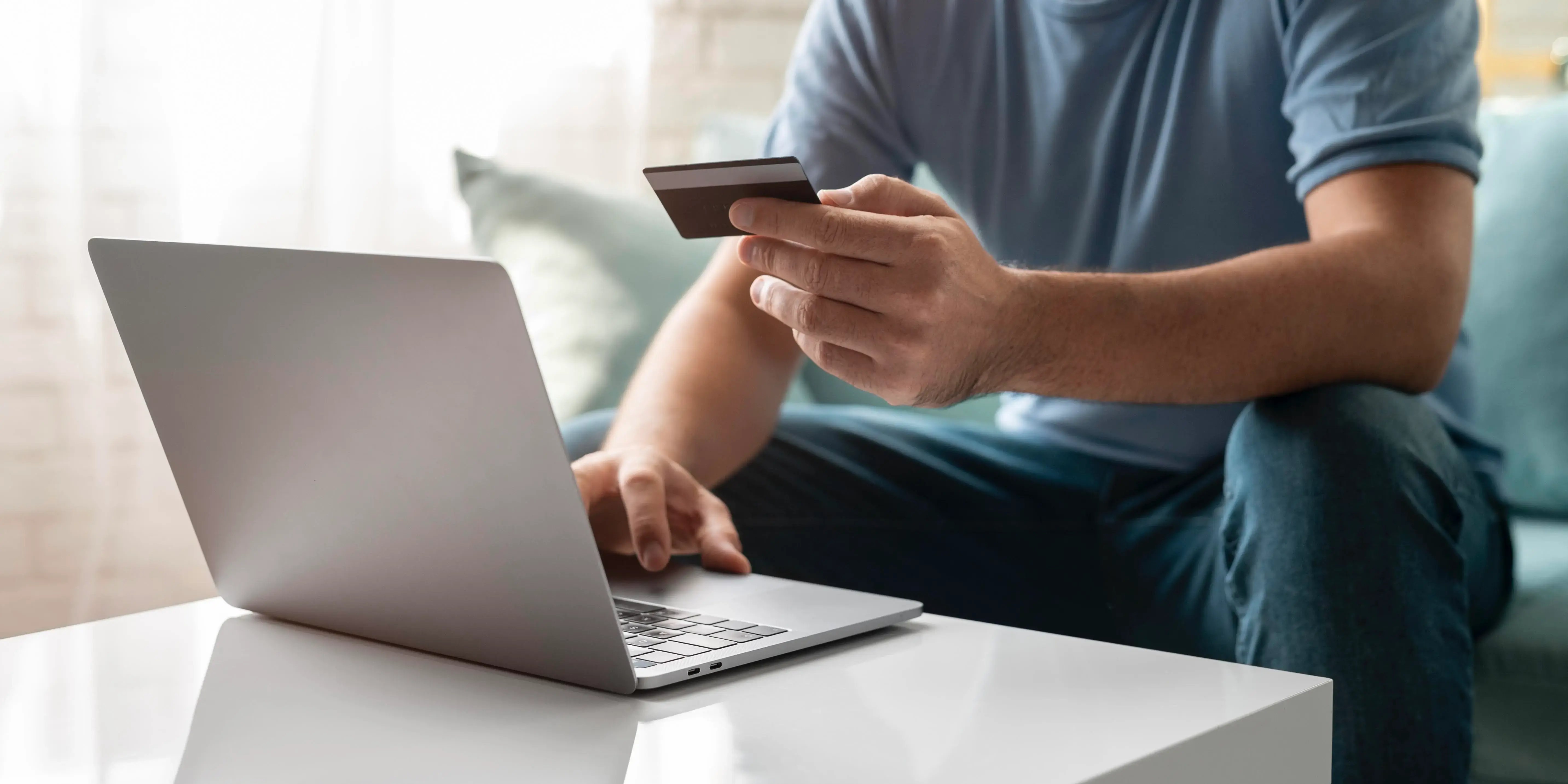 Hombre en computadora con tarjeta de crédito. Banorte en línea para comprar tu hogar
