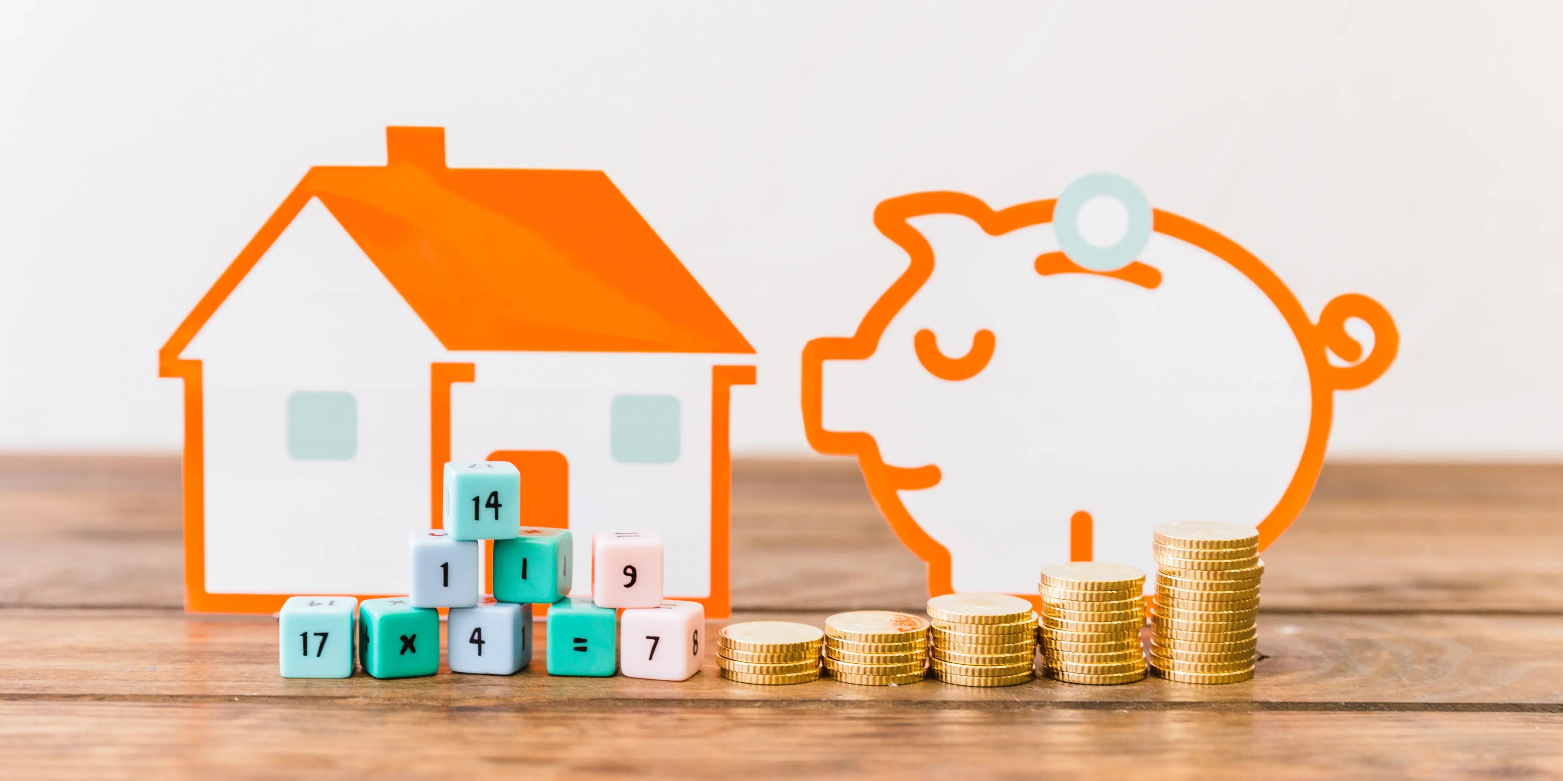 Casa y alcancía de cerdo de papel con monedas al frente. Propósito de comprar casa.