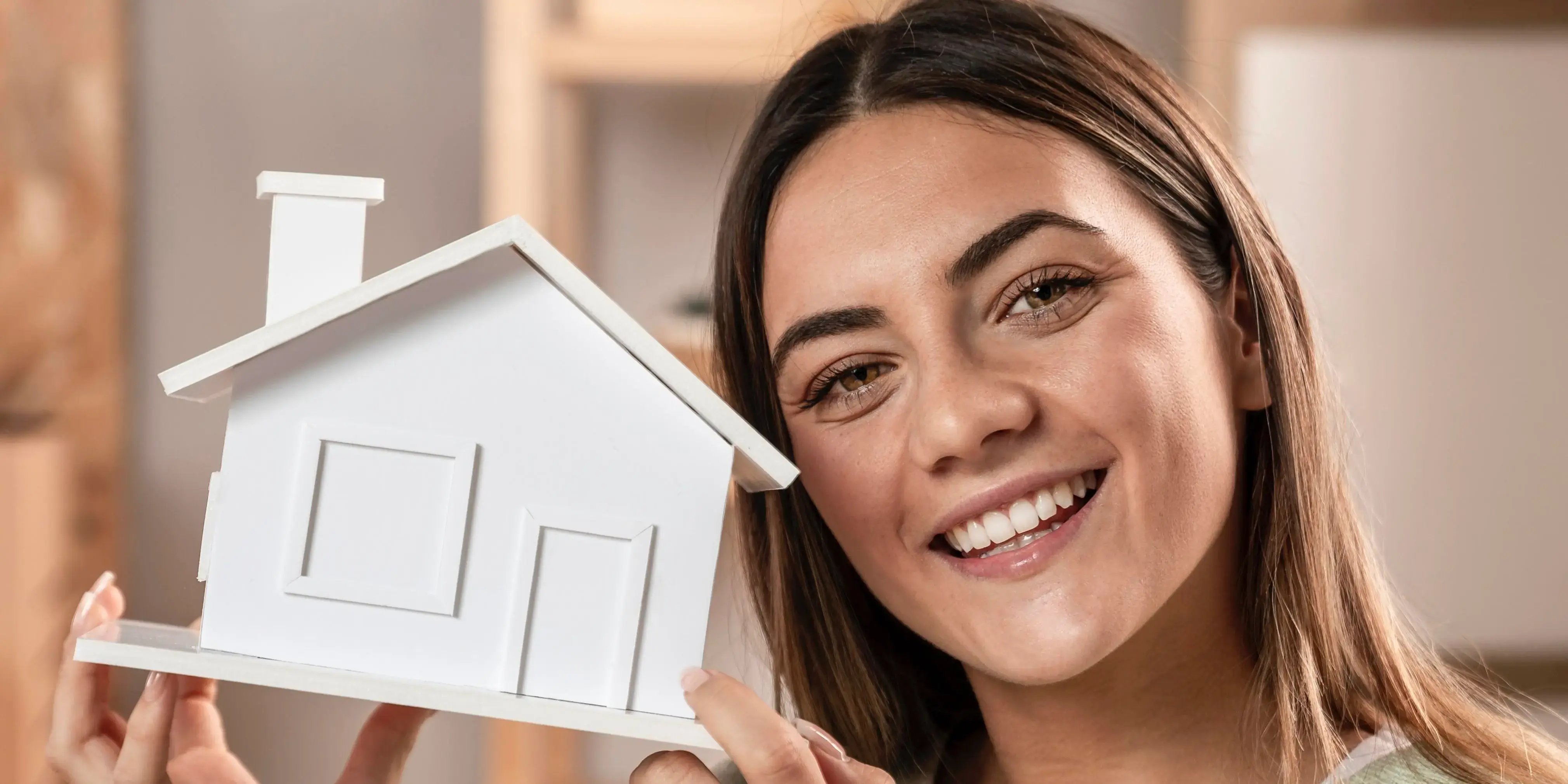 Mujer sosteniendo una casa blanca de madera. Casa nueva o usada