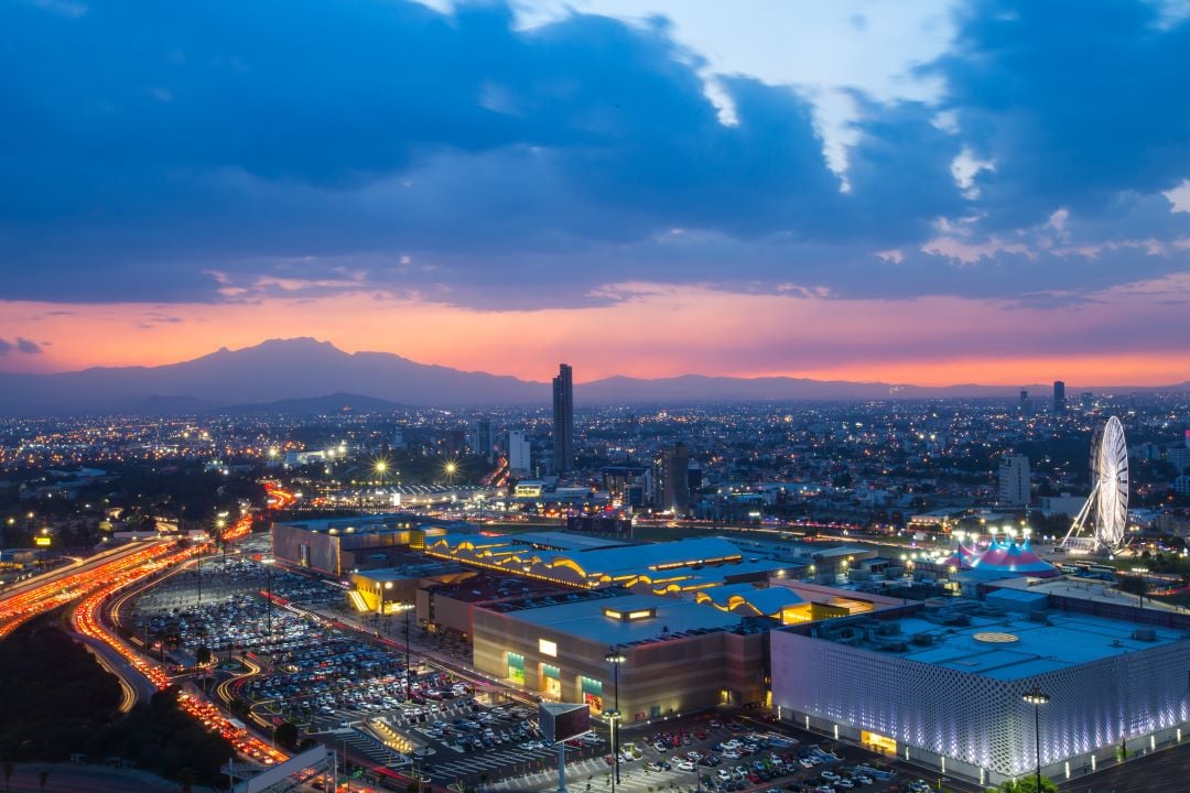 Ciudad de Puebla, vista panorámica donde se ven carros transitando, la rueda de la fortuna, y es de noche.