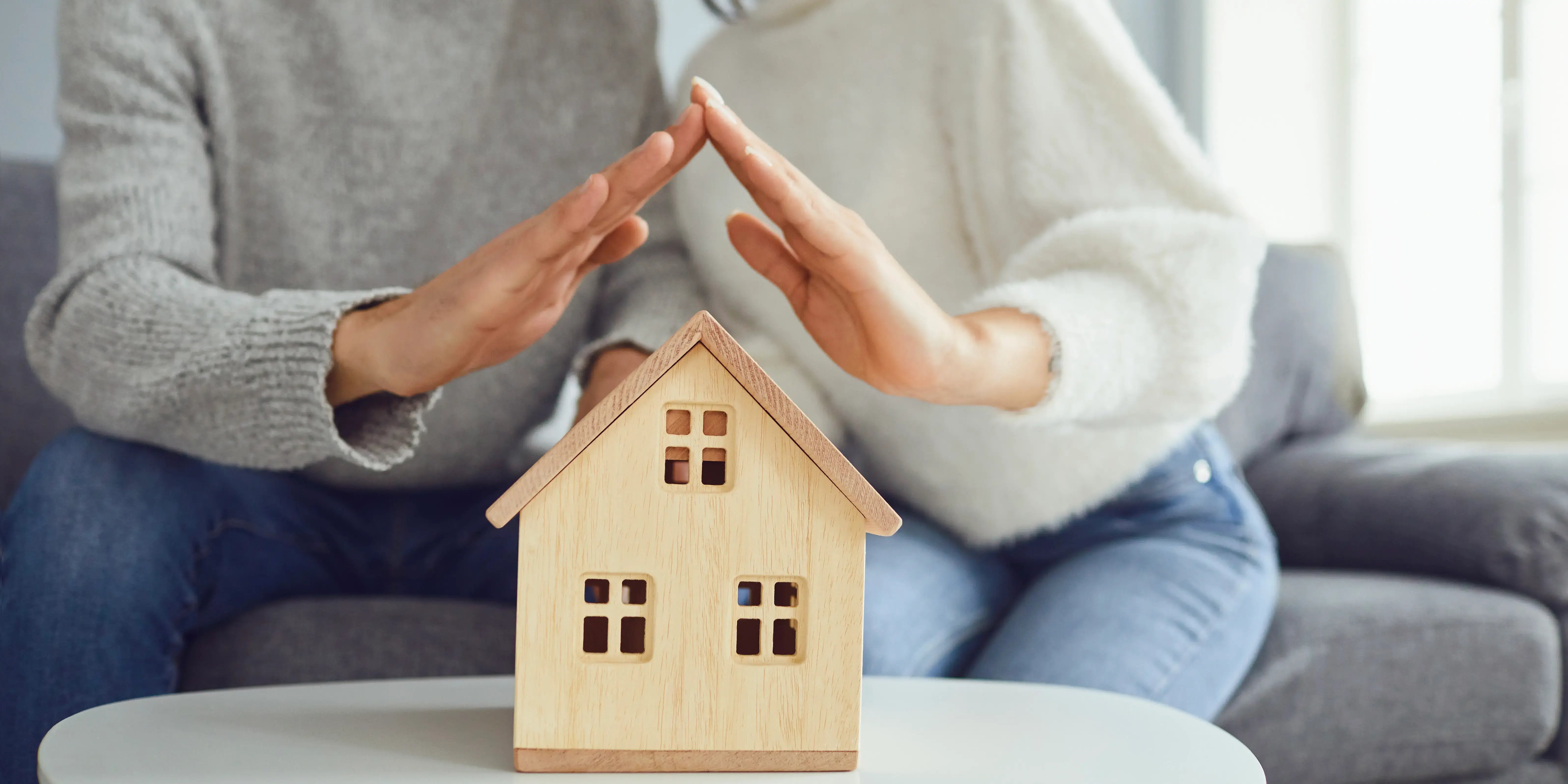 Pareja con sus manos al rededor de una casa. Tener tu propio espacio