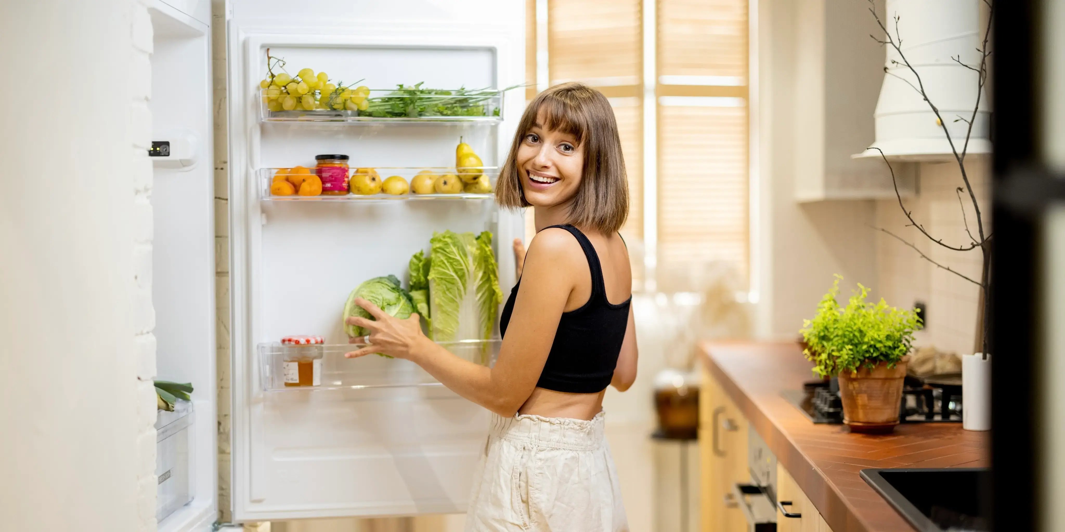 Mujer joven guardando la comida en el refrigerador cuando vive solo.