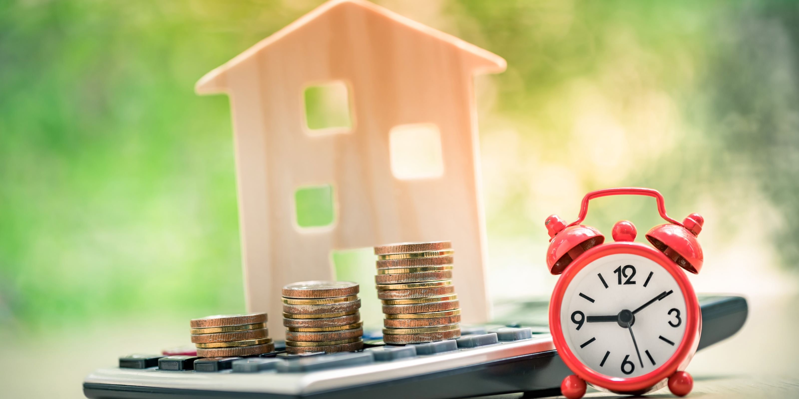 Estrategias para pagar tu hipoteca lo más pronto posible. Reloj, dinero, calculadora y pilas de dinero en la imagen. 