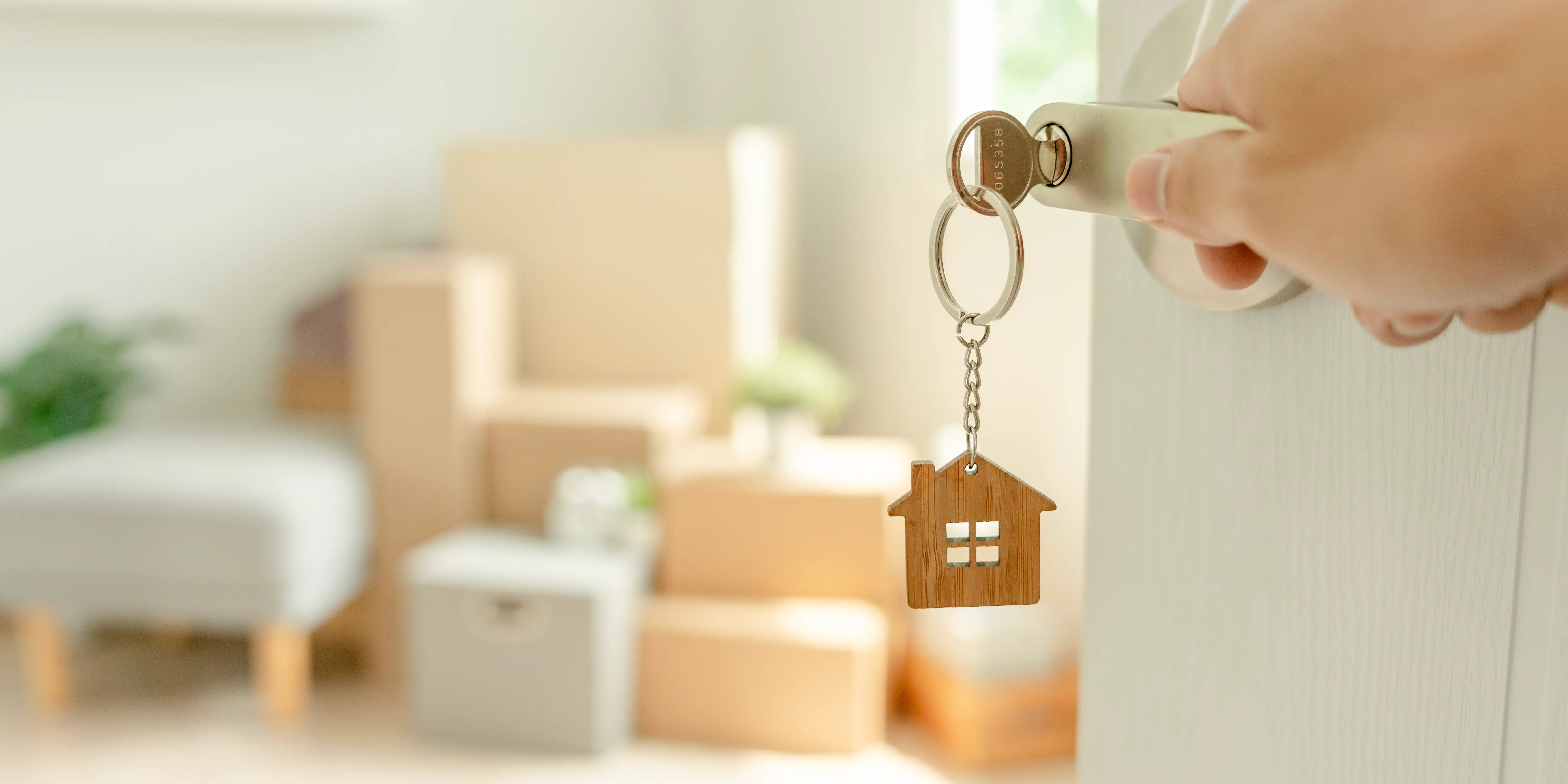 persona abriendo la puerta de su casa y con cajas de mudanza al fondo. Casa propia