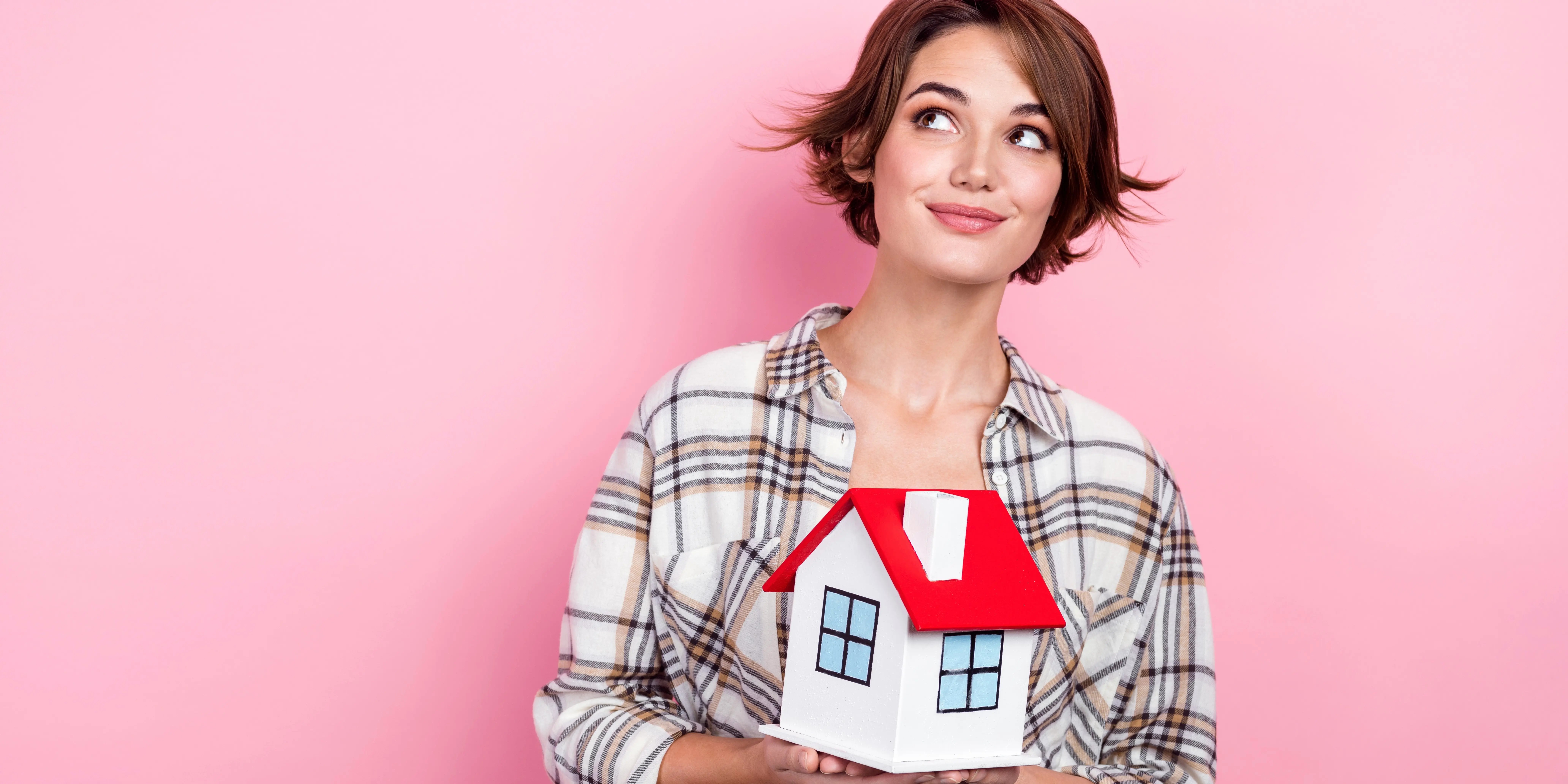 Mujer sosteniendo una casa de madera preguntándose si conviene comprar una casa en preventa