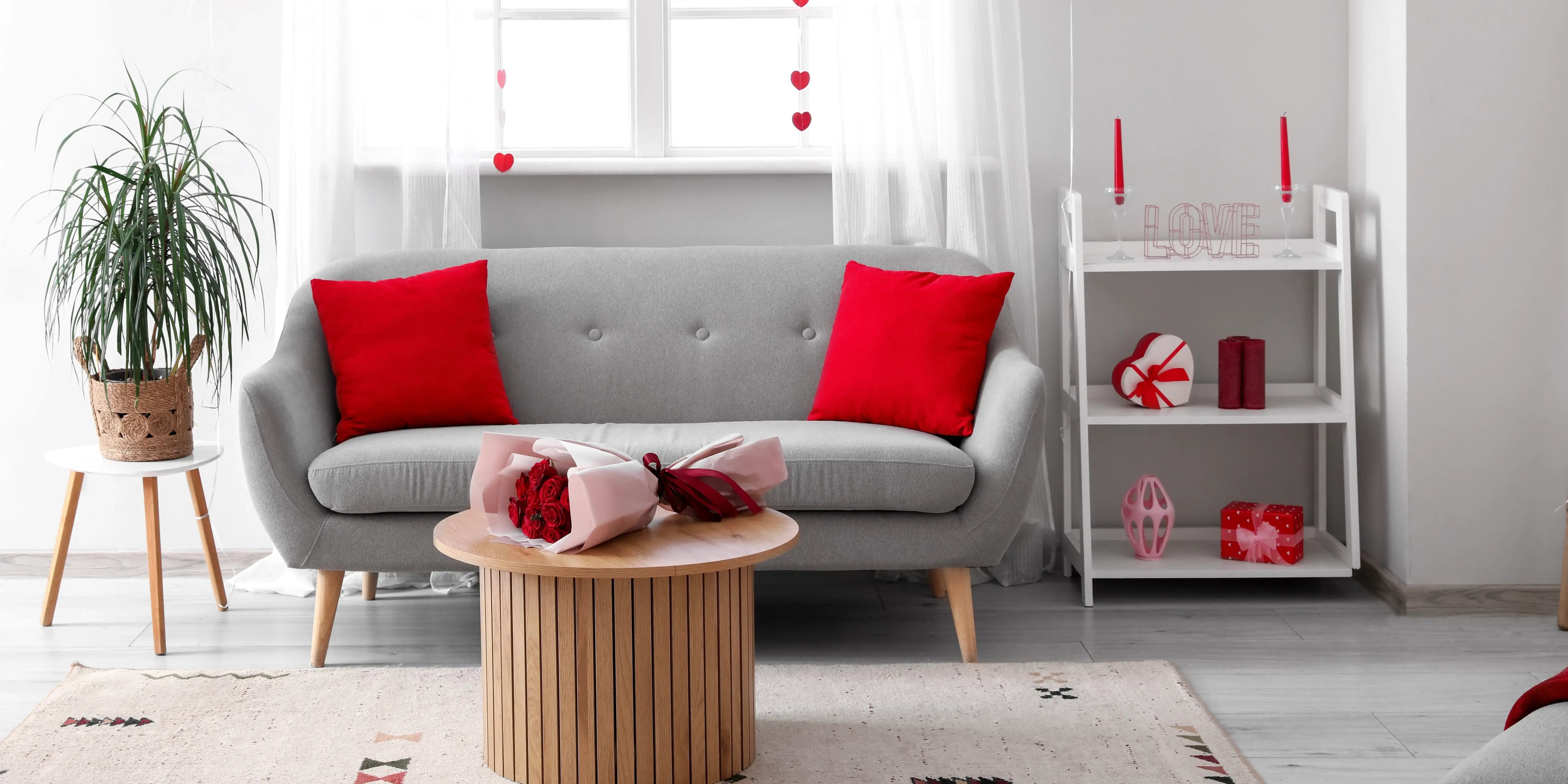 Sillón con cojines rojos y un ramo de rosas sobre la mesa. Decora tu departamento San Valentín