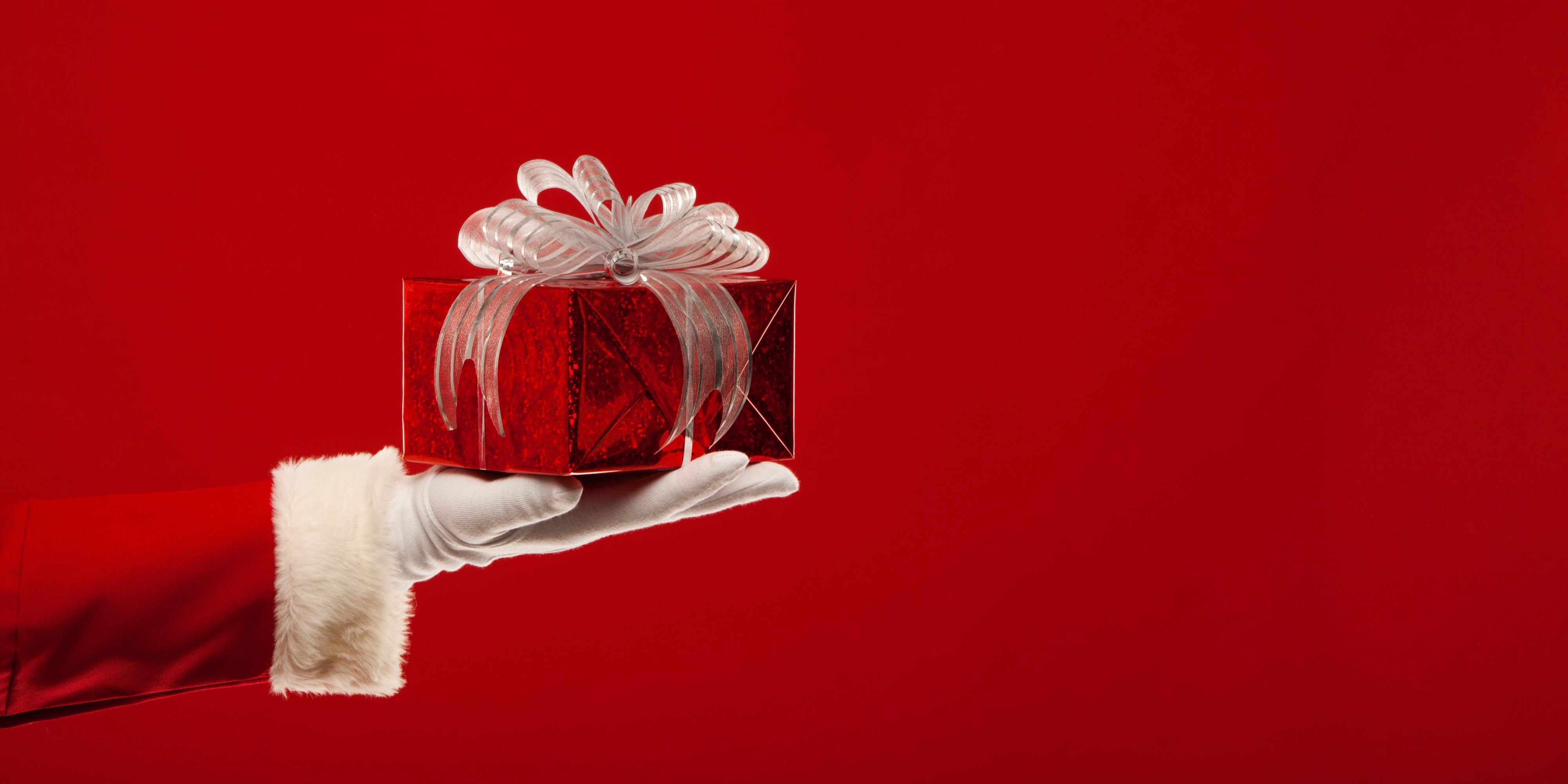 Ideas originales para regalos de navidad. Brazo de Santa Claus sobre sale con un obsequio en mano para dar una idea de regalo de navidad.