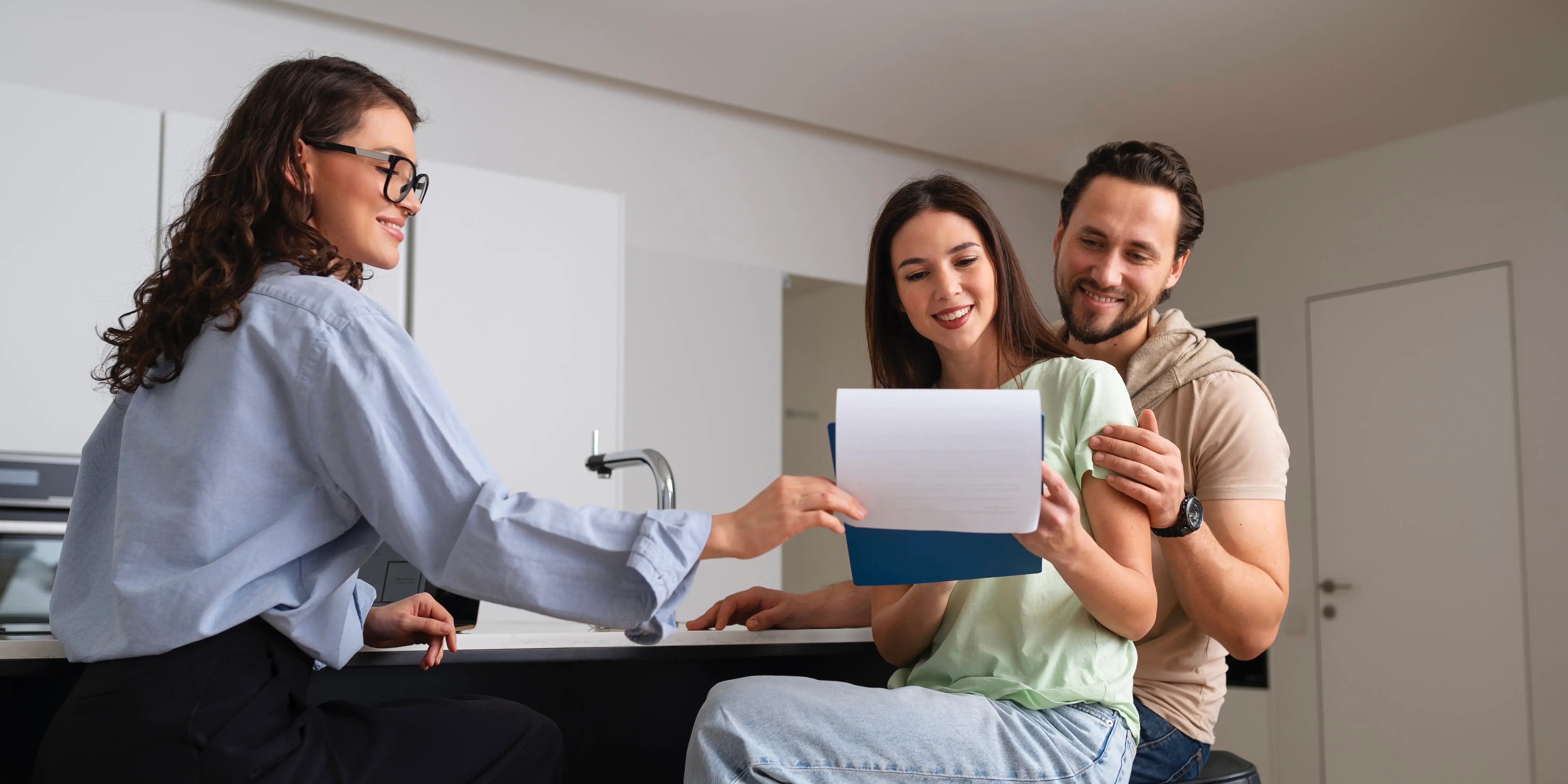 Bróker enseñándole papeles a una pareja. Propósito de comprar casa.