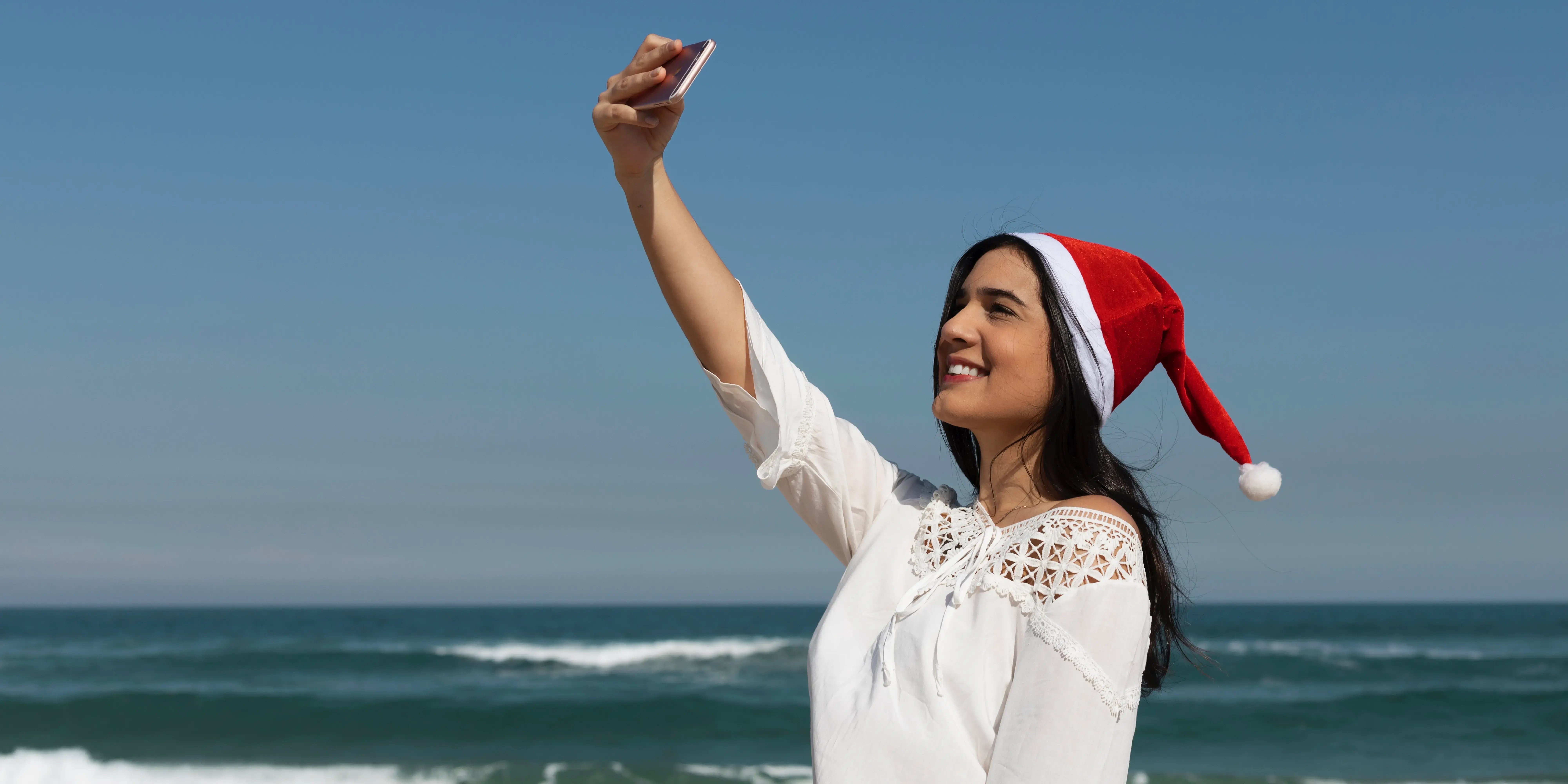 Mujer con gorro de santa claus tomándose una selfie.Navidad en Quintana Roo